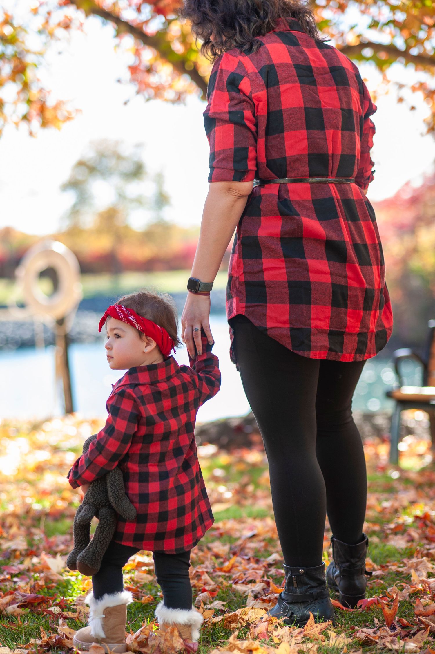 Matching red and black buffalo plaid outfits shown in autumn leaves during outdoor photoshoot.