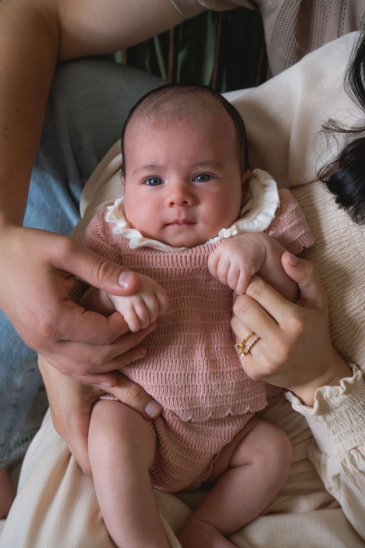 Close-up sequence of a baby in a pink romper being held and cuddled.