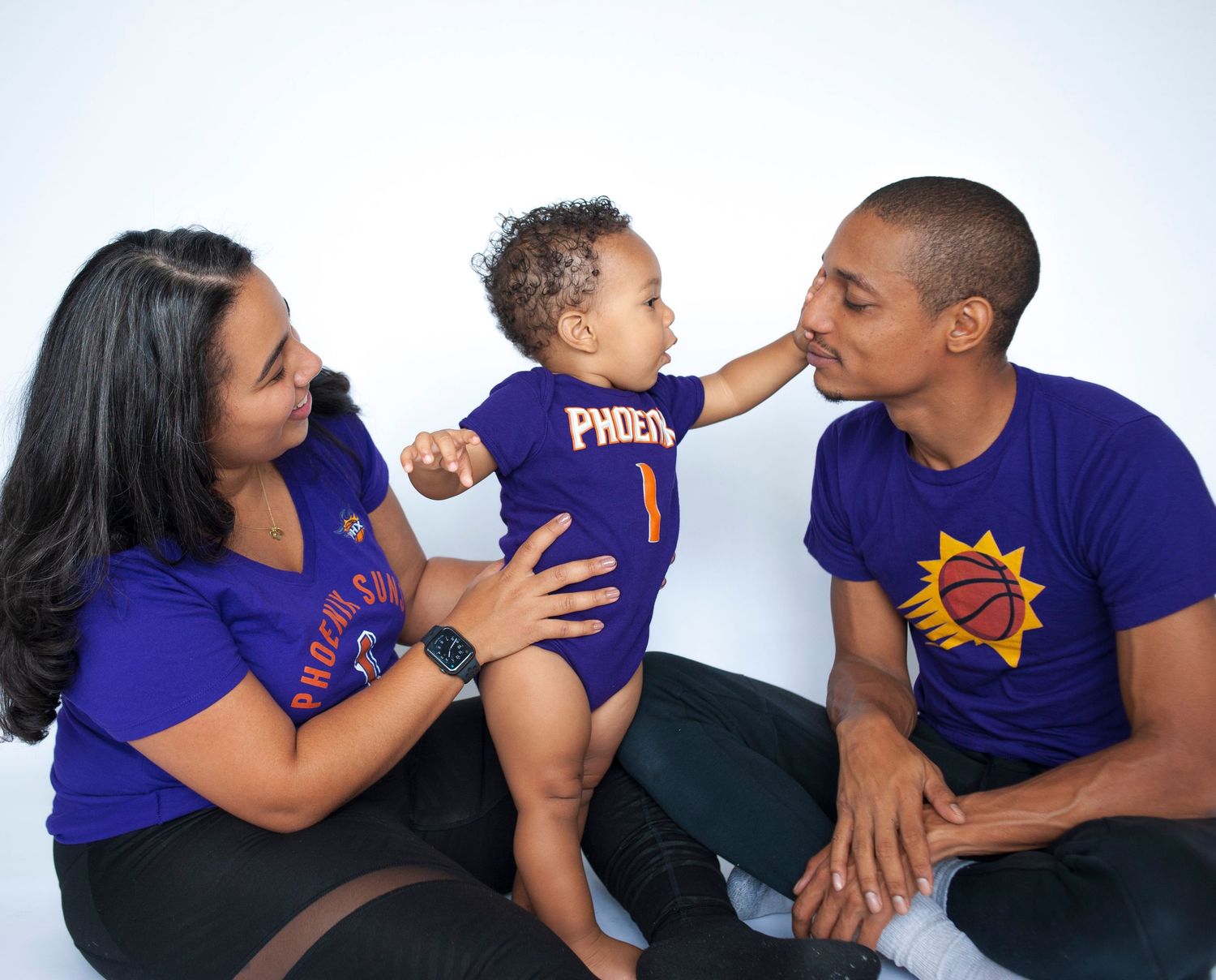 A family wearing matching purple shirts sharing affectionate moments together.