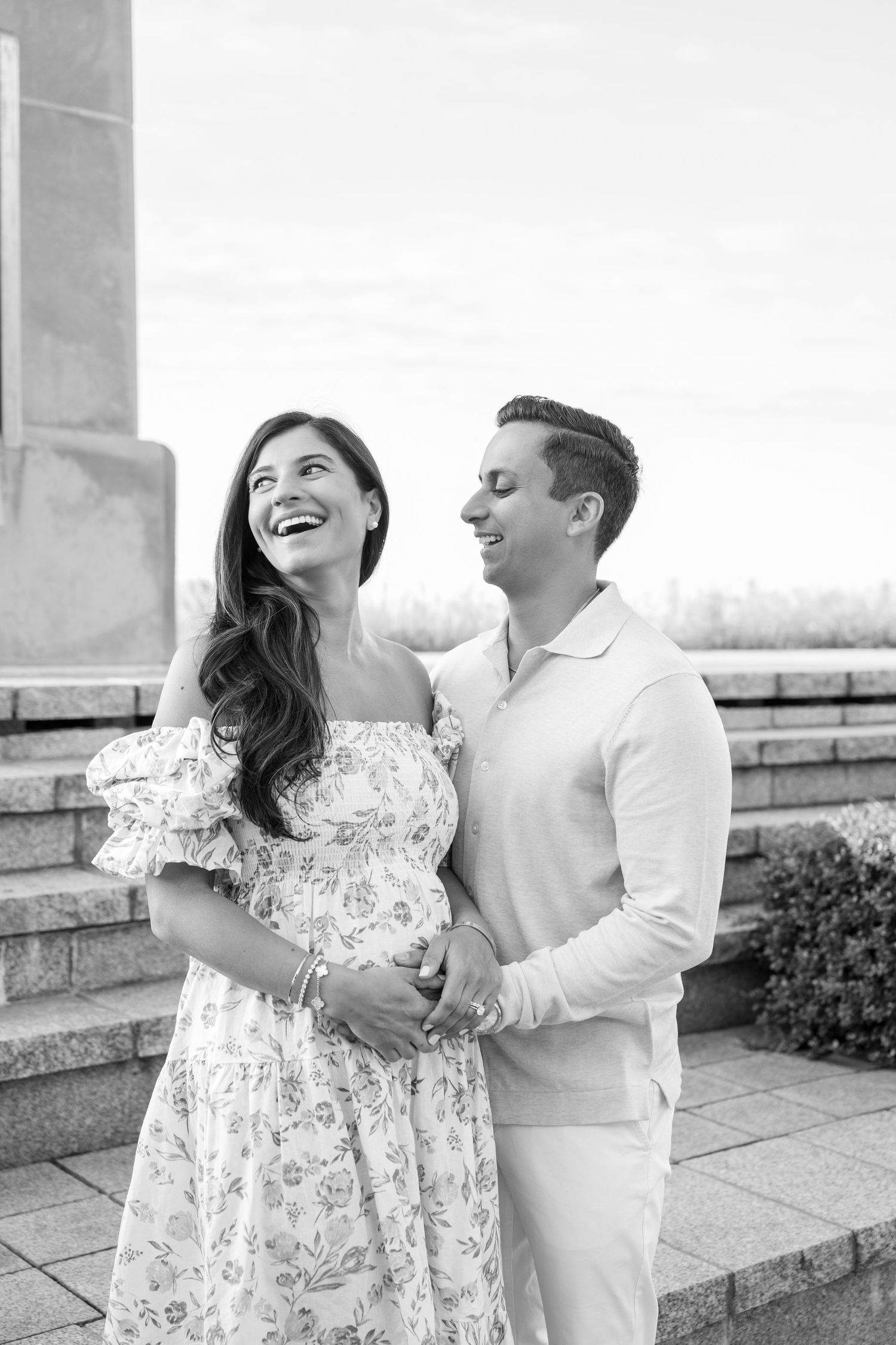 Couple shares romantic moment outdoors while laughing together in black and white.