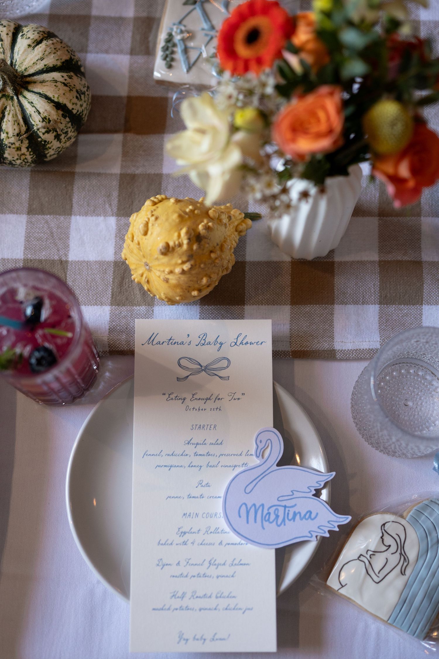 Wedding stationery and floral decorations arranged on a checkered tablecloth with coral flowers and delicate details.
