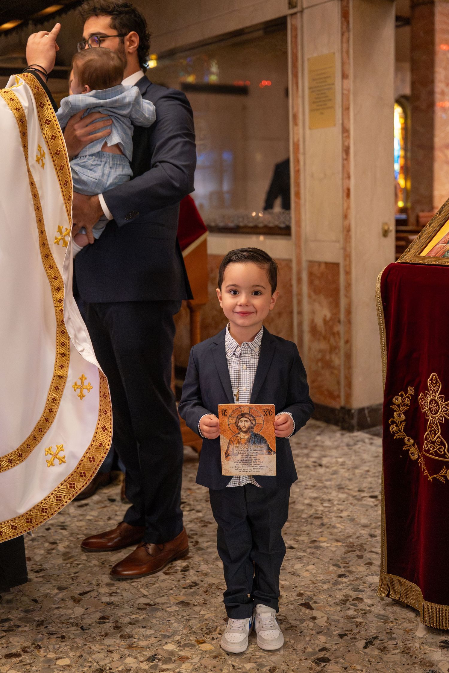 Young child in formal attire standing near ornate church pews.