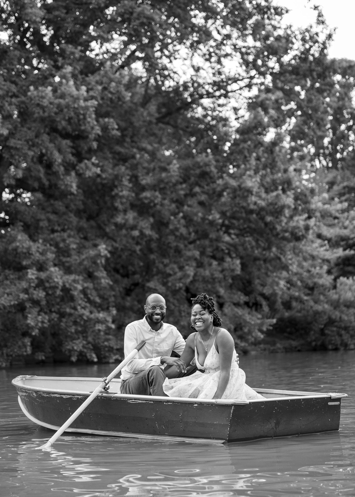 A couple enjoys a peaceful moment together in a rowboat on a tranquil lake.