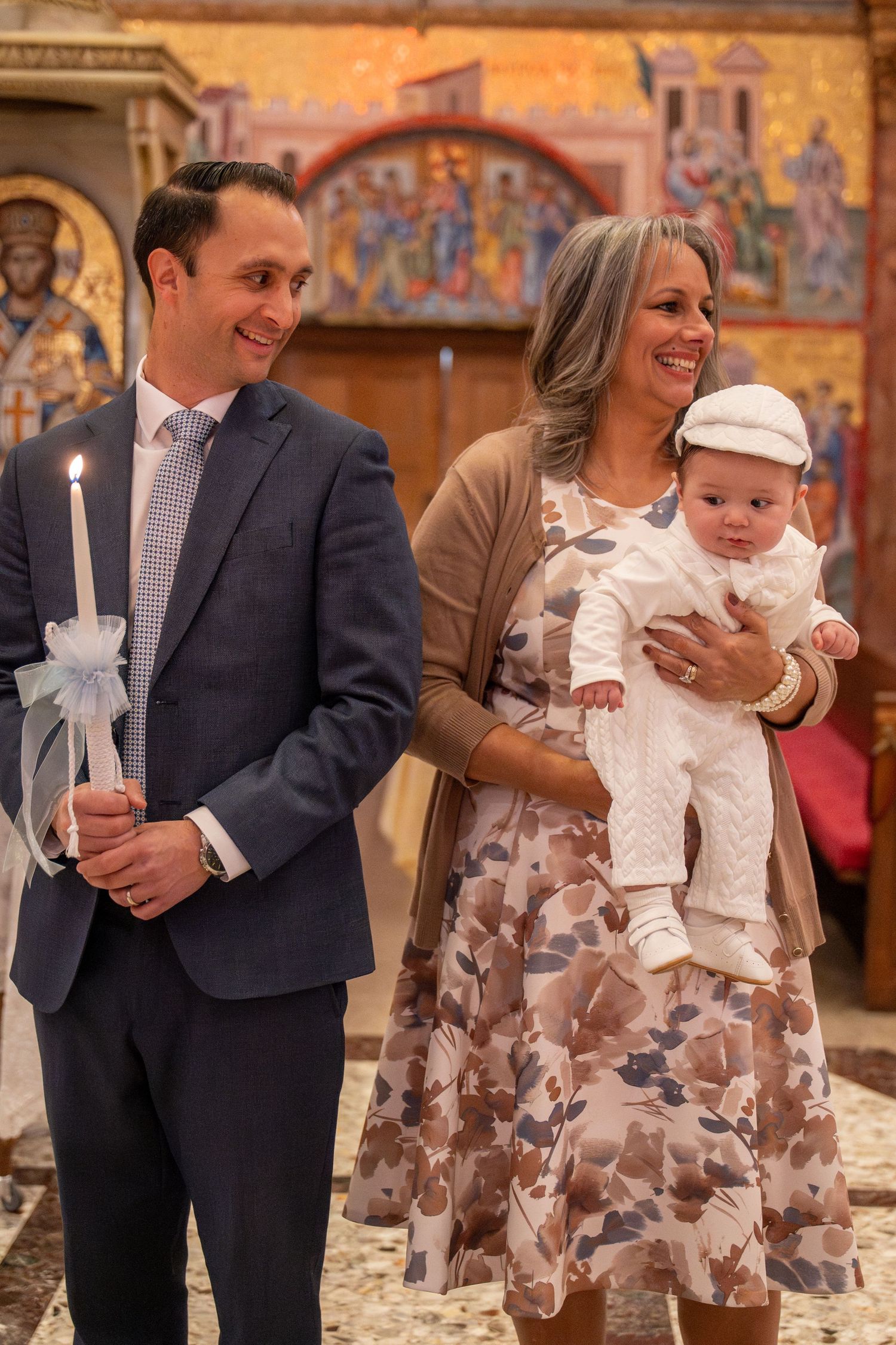 A baptism celebration in an ornate church with decorated candles and religious iconography.