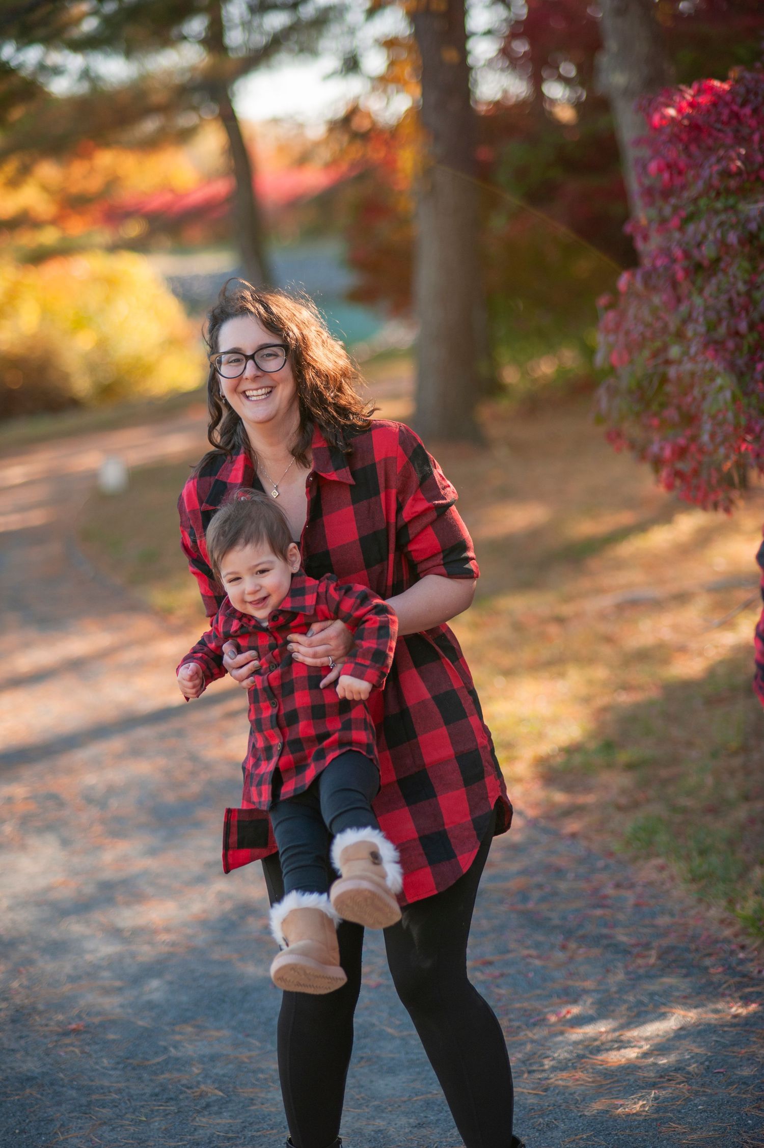 Matching buffalo plaid outfits on a scenic autumn path with colorful fall foliage.