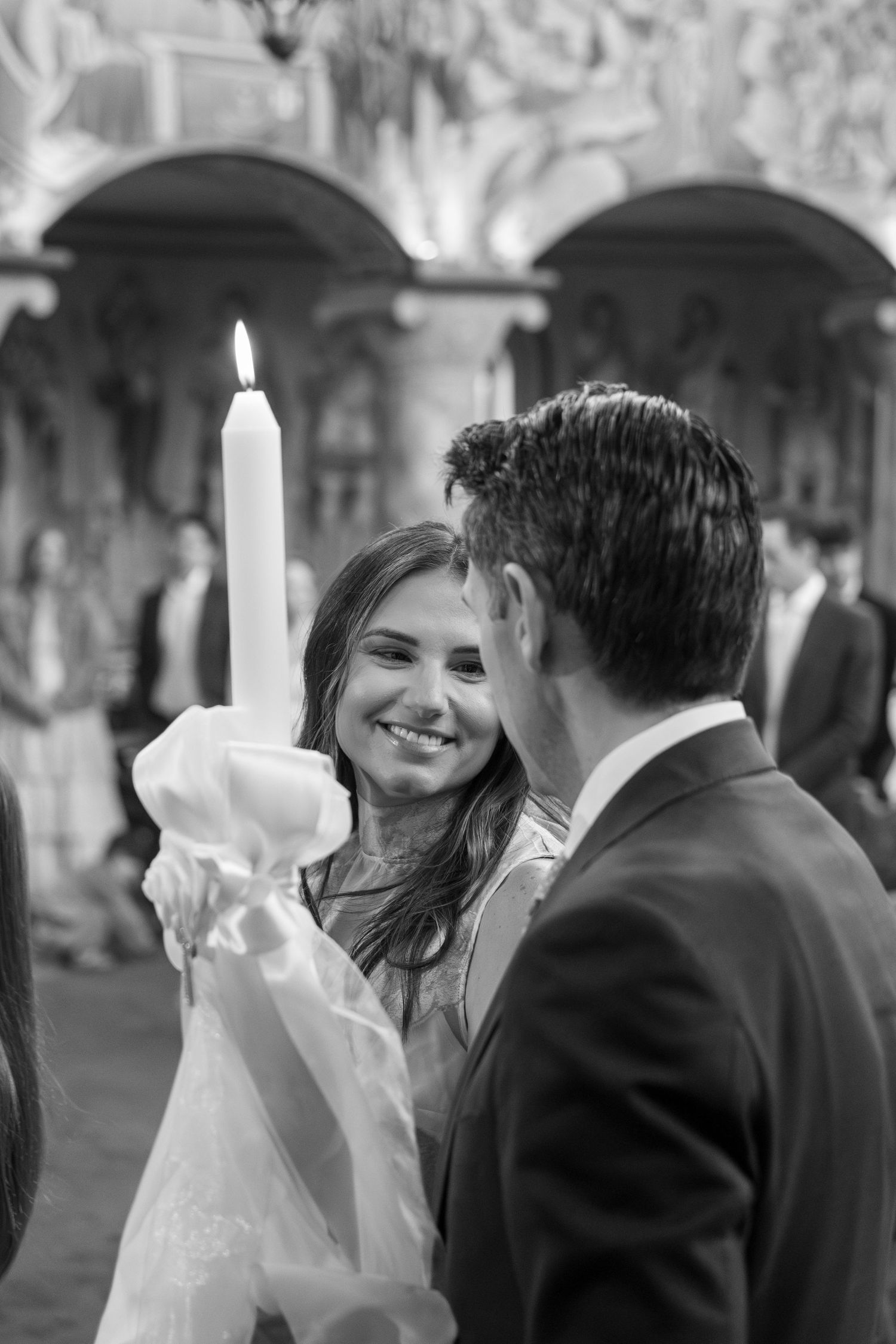 Bride and groom holding candle during Orthodox wedding ceremony in black and white photograph.