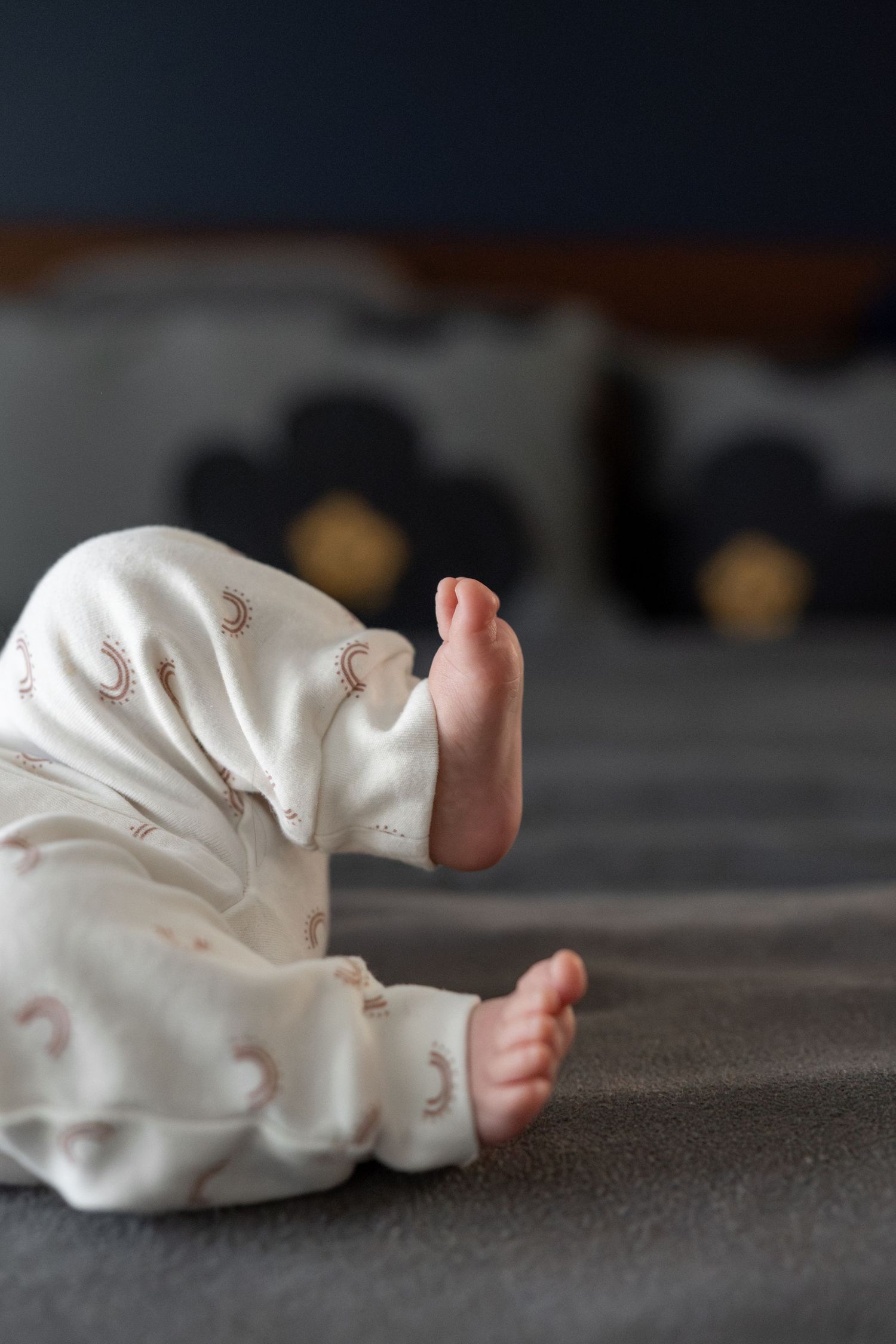 Close-up series of tiny baby feet in white socks against a gray textured background.