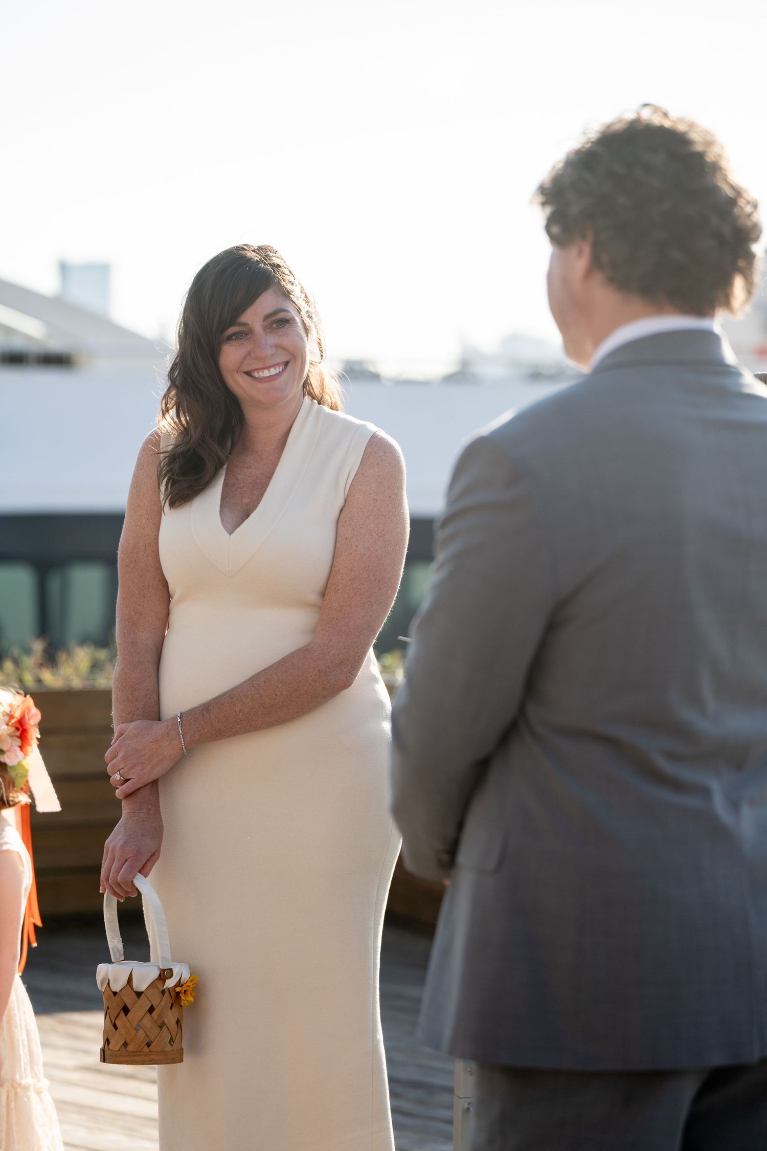 A couple shares a tender moment during their wedding celebration on an outdoor deck at sunset.