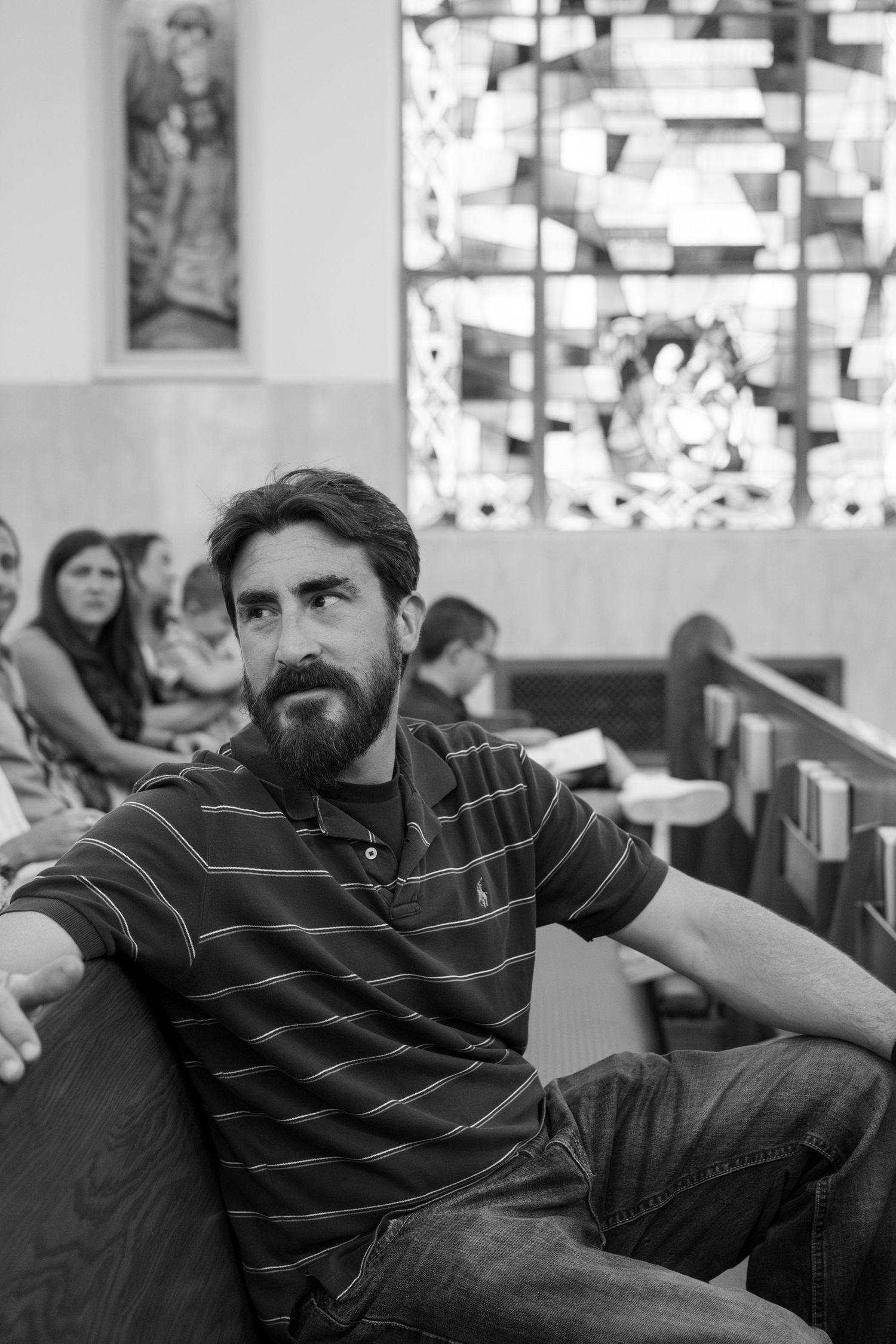 A person in a striped polo shirt sits casually in what appears to be a cafe or restaurant setting.