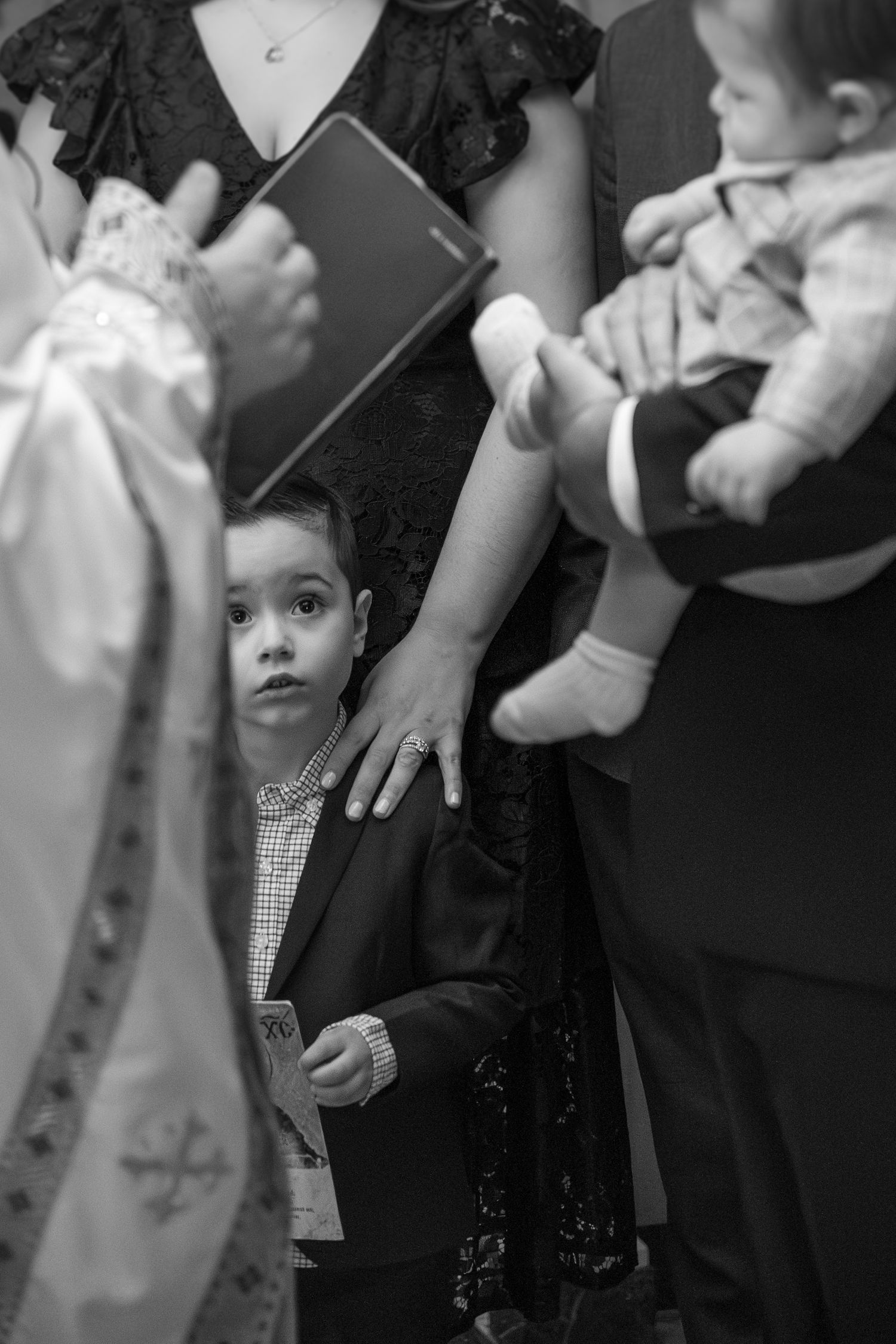A black and white candid photograph capturing a quiet moment during a formal gathering.