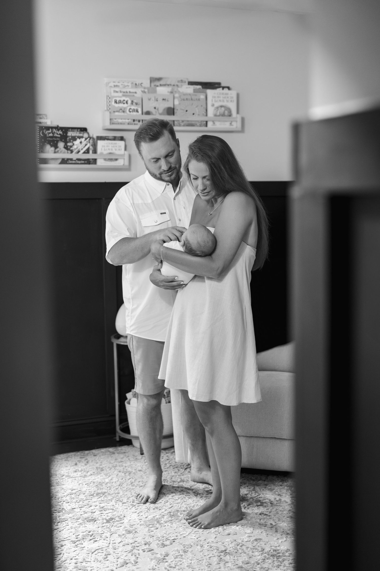 Black and white photo of parents sharing an intimate moment with their newborn.
