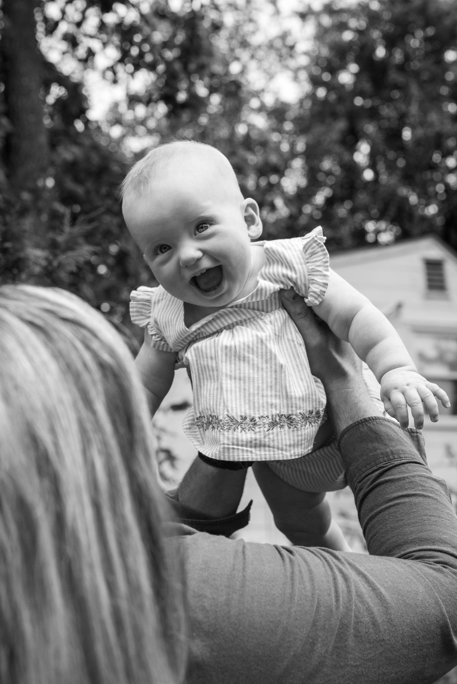 Black and white sequence of a smiling baby in a striped outfit being held up playfully.