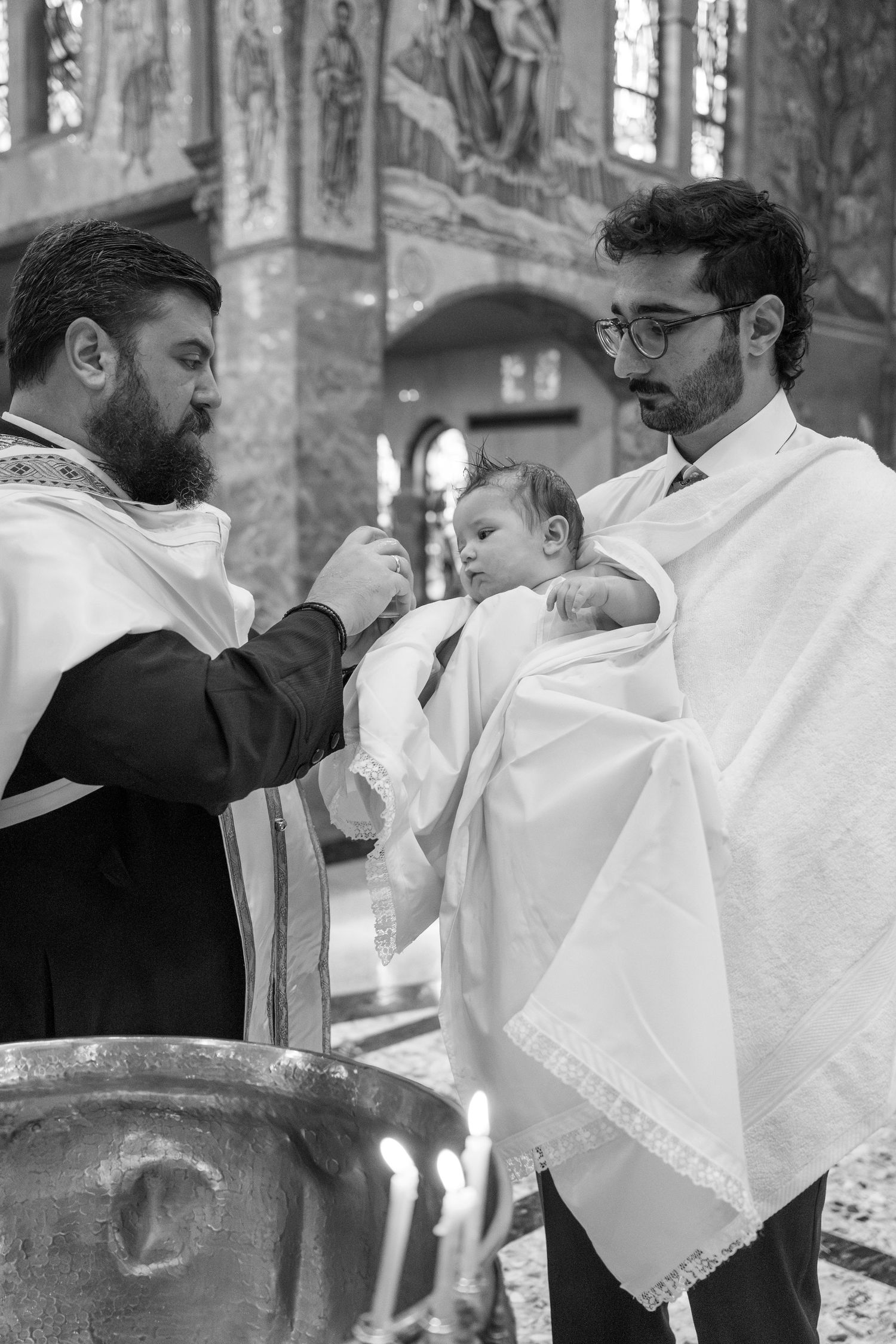 A religious baptism ceremony being performed at an ornate church font.