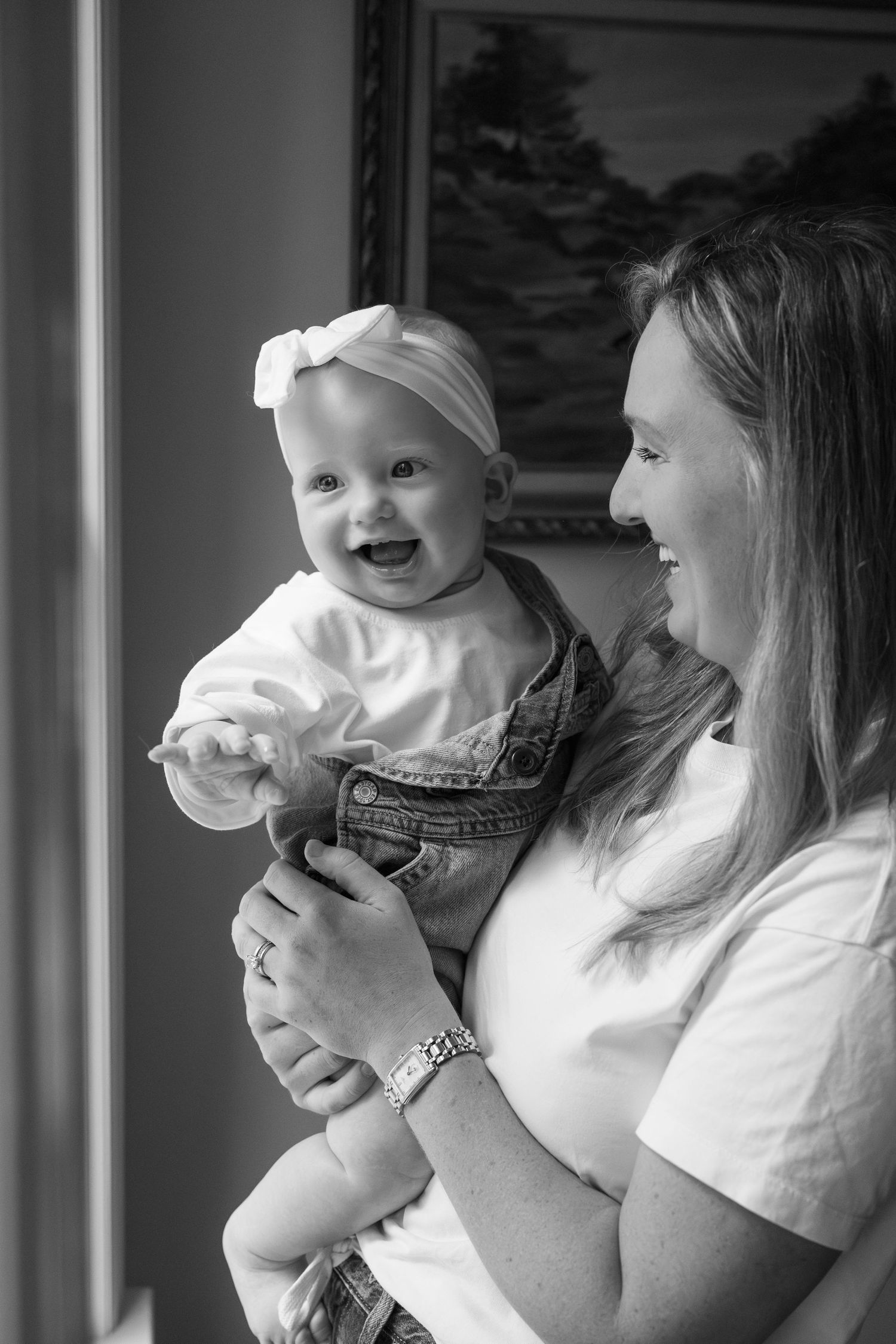 A joyful moment captured in black and white as a baby in overalls shares a laugh.