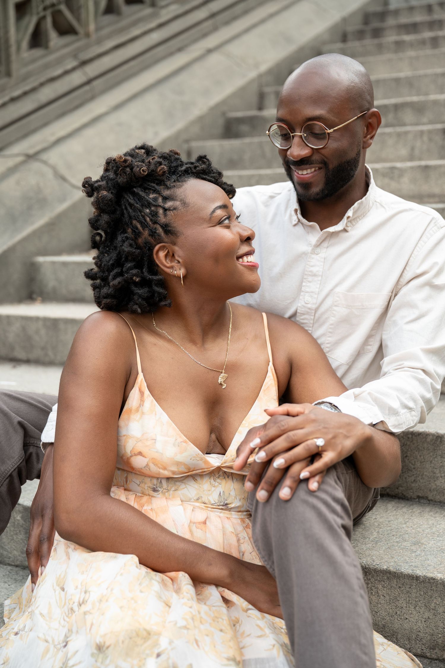 A couple shares a joyful moment sitting together on stone steps outdoors.