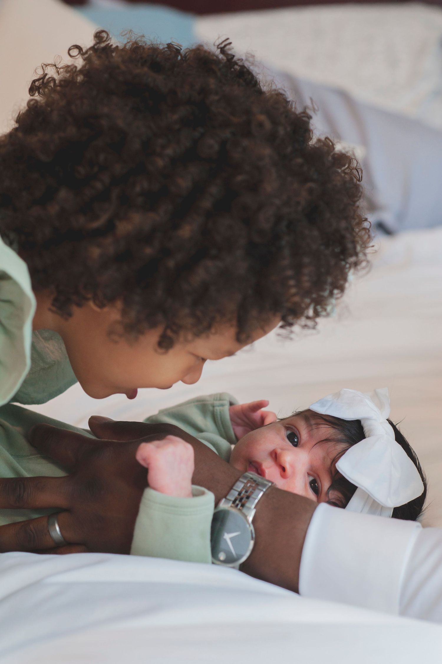 Close-up photos showing tender moments between family members on white bedding.