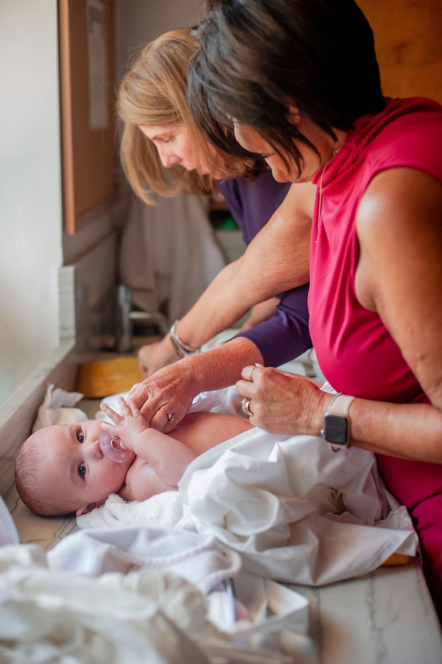 A baby in white clothing lies on a table during a ceremony.
