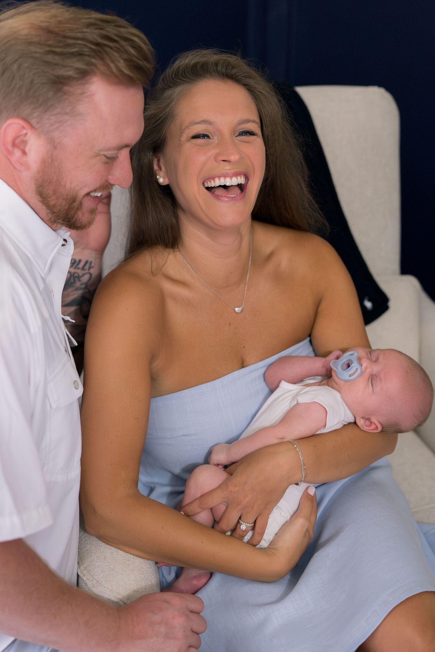 Tender family moment with newborn baby being cradled in a light-filled room.