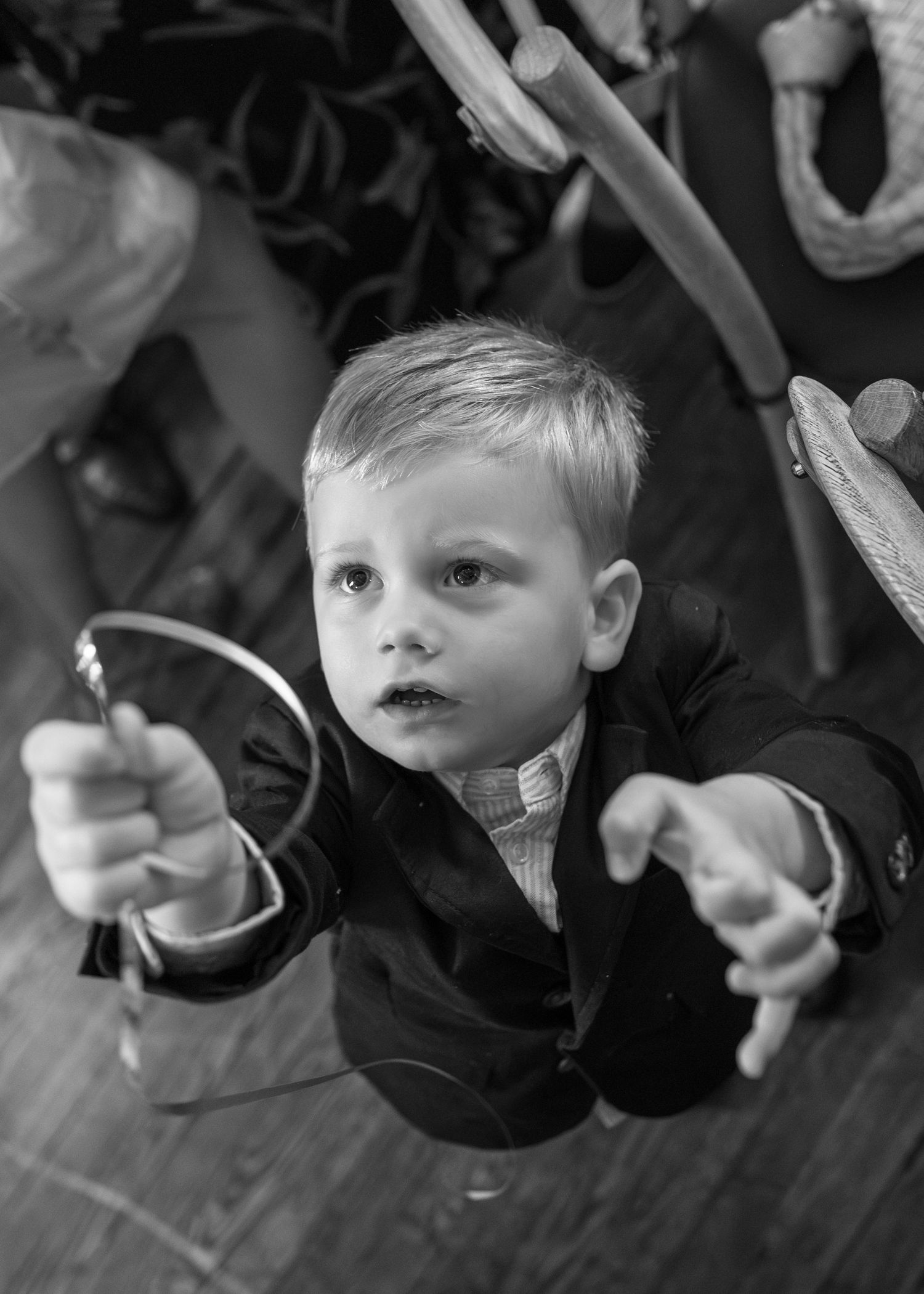 Young blonde boy in suit reaching toward camera at formal event in black and white.