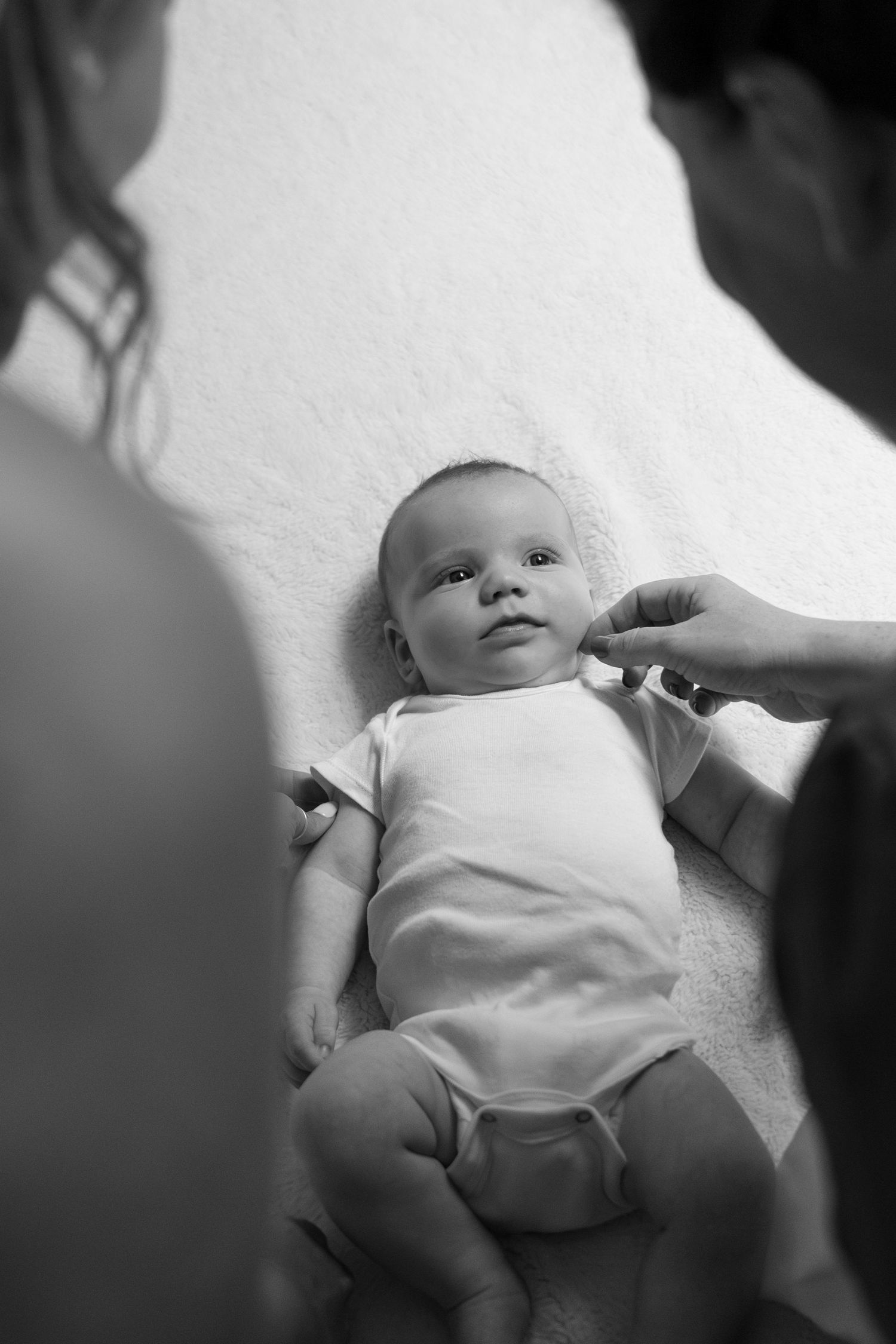 A black and white photo series shows a baby lying on a white surface being examined during a medical checkup.