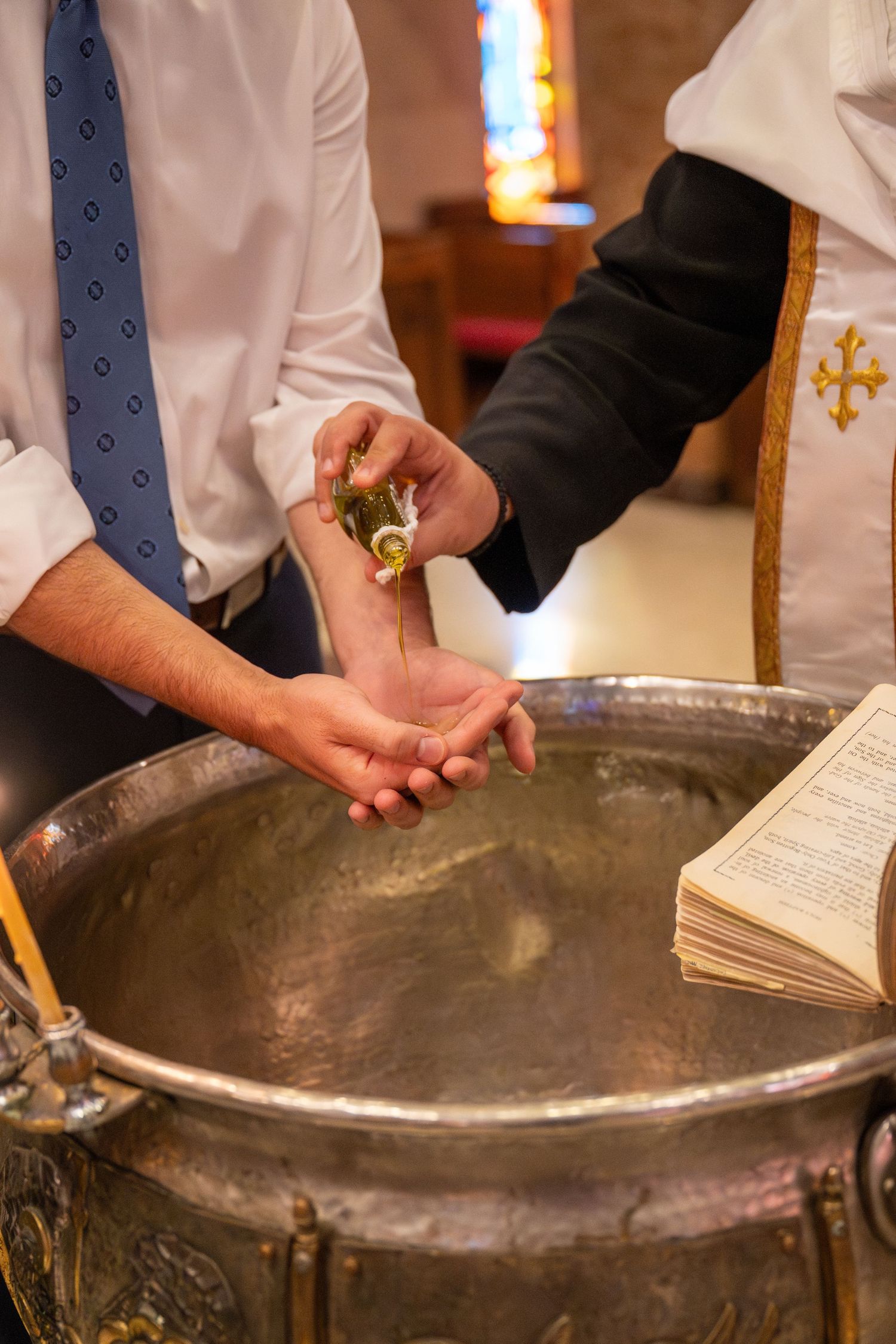 A baptismal font in a church with hands holding a religious text during a baptism ceremony.