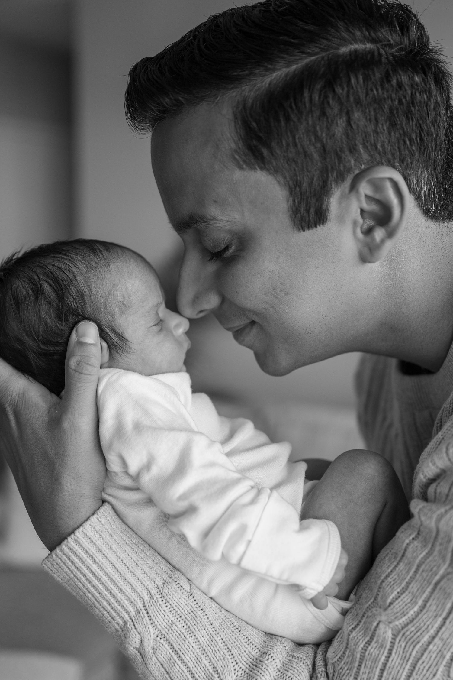 Tender black and white portrait of a newborn baby being held close.