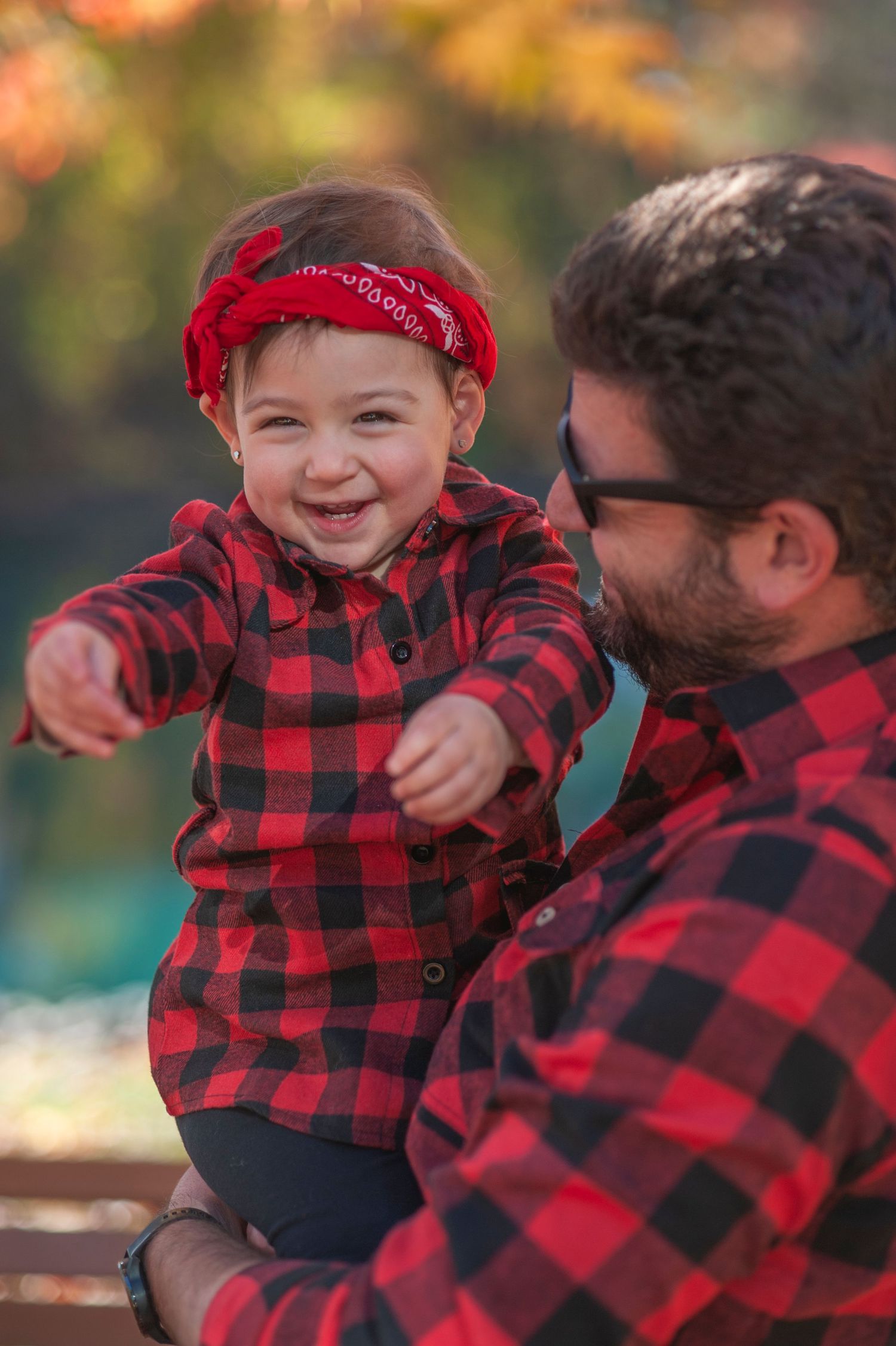 A joyful moment shared between two people wearing matching red and black buffalo plaid shirts outdoors.