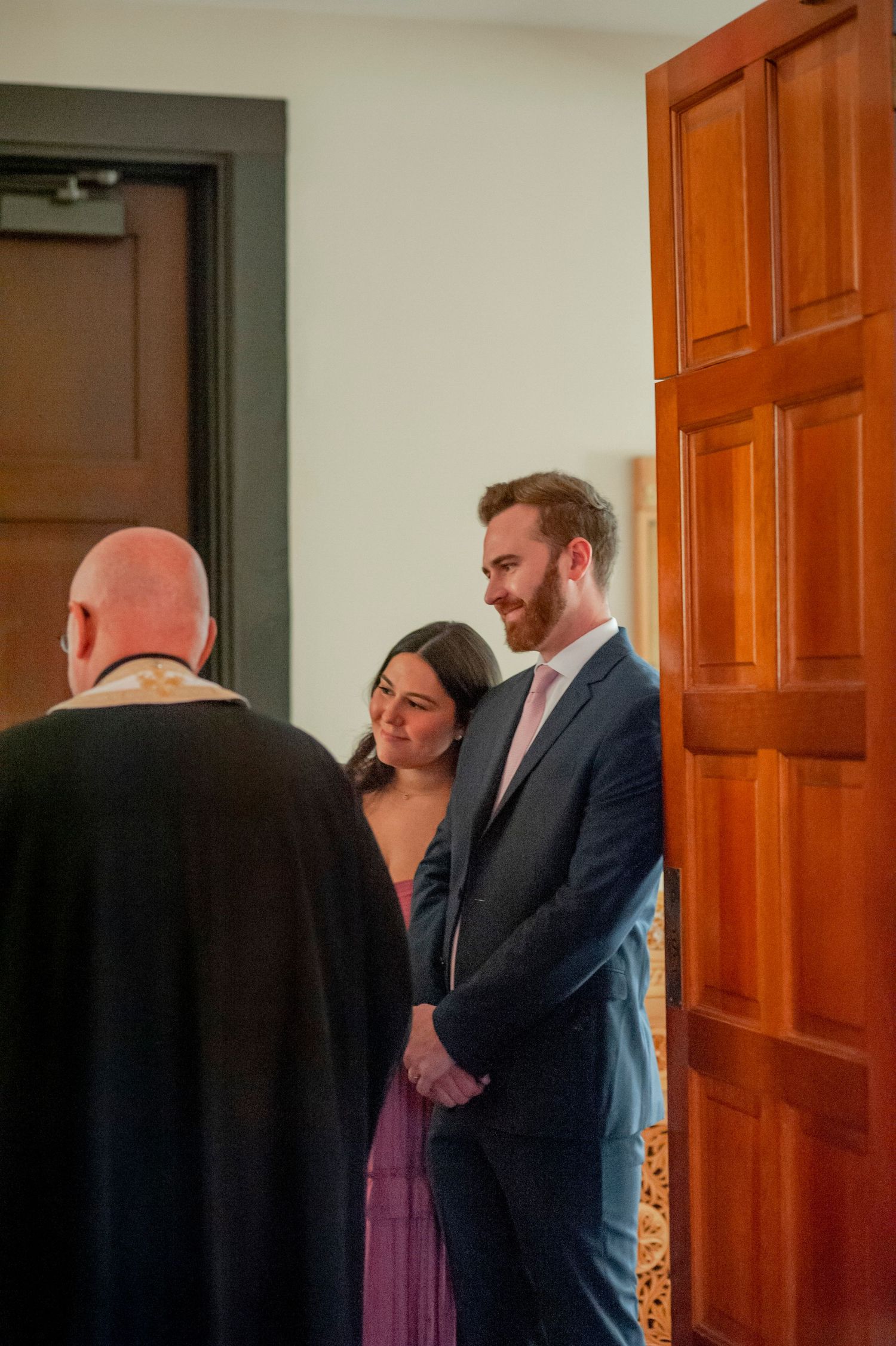 People standing in front of an orange wooden door during what appears to be a formal event.
