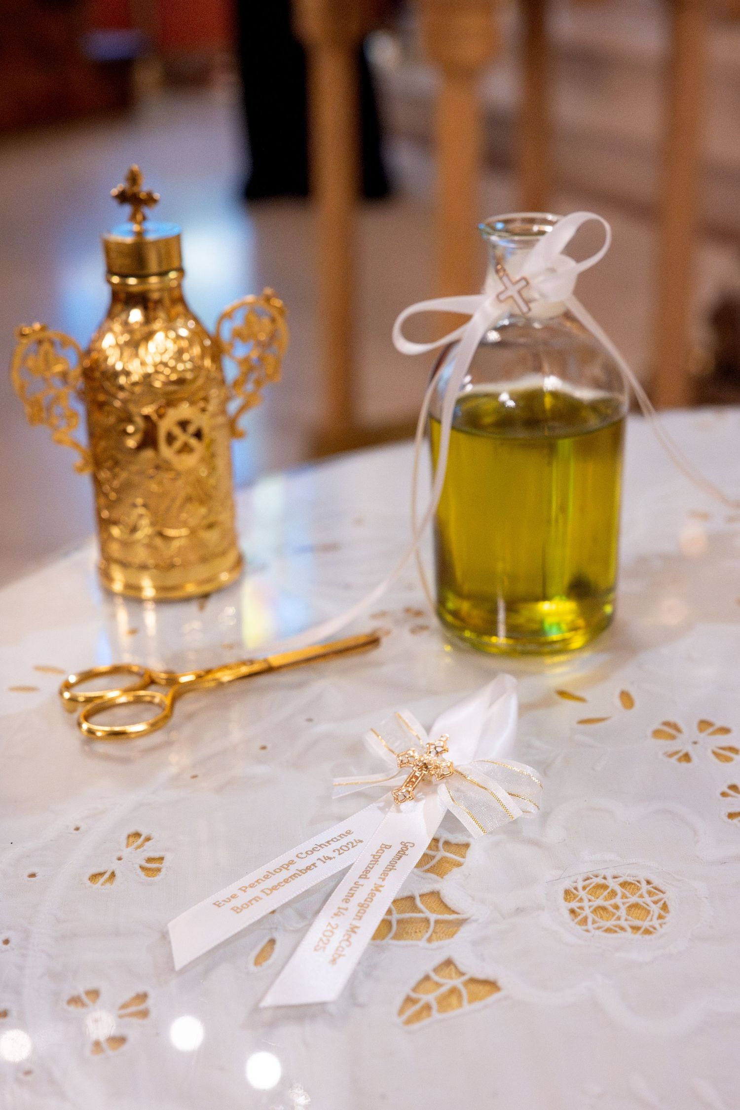 Golden ceremonial oils and vessels arranged on white cloth during a religious ceremony.