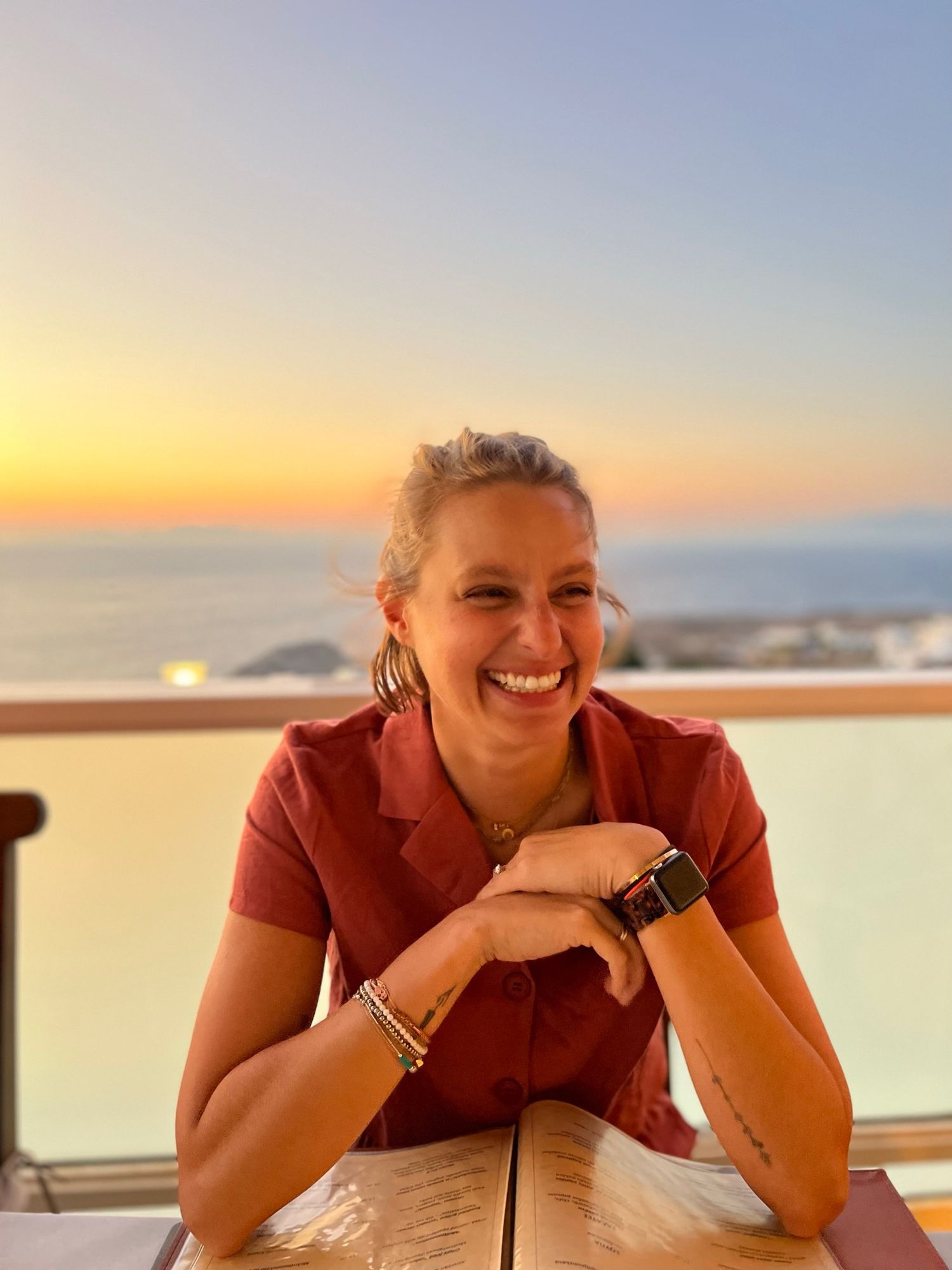 Person in red shirt enjoying sunset view from outdoor deck.