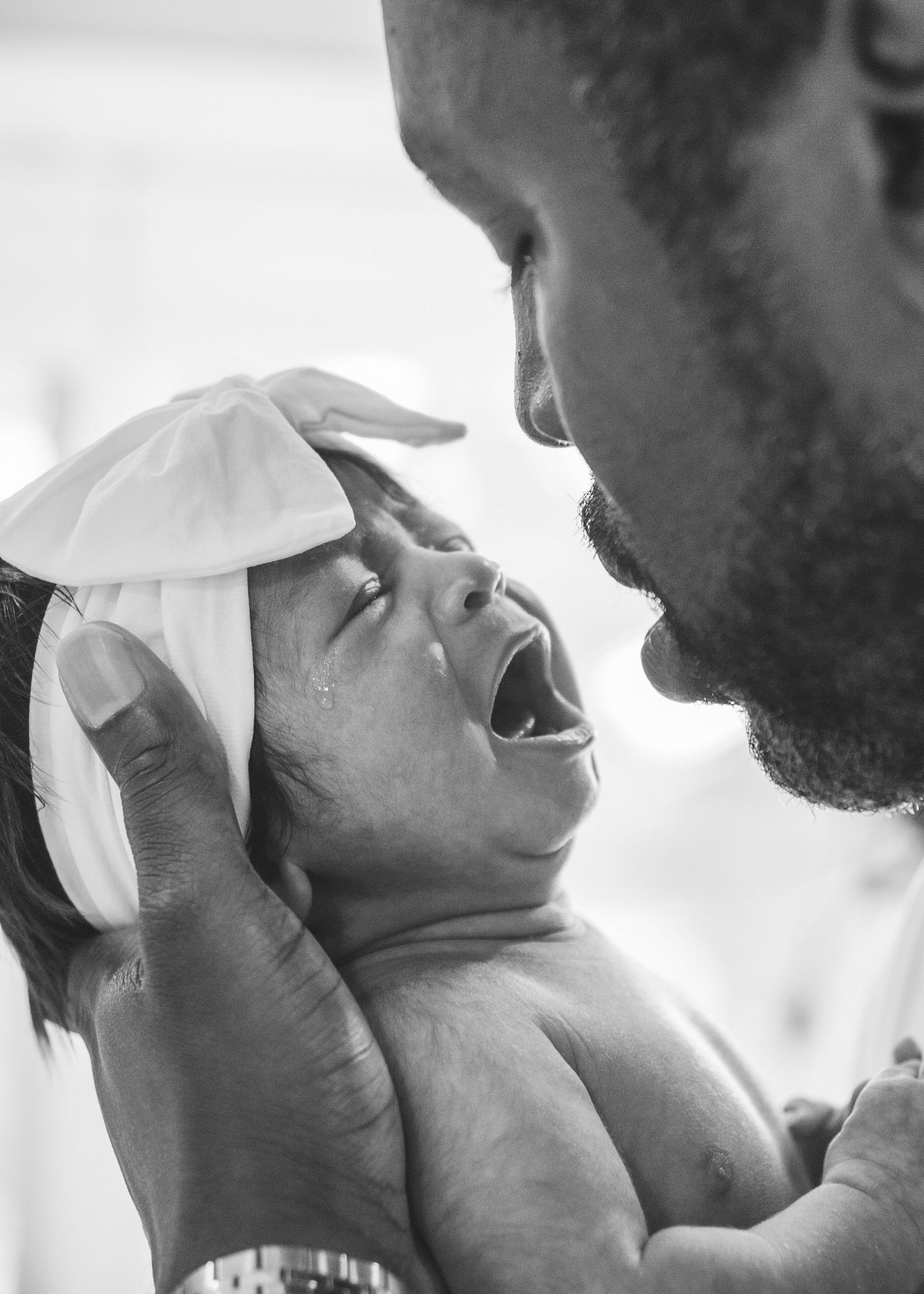 A black and white portrait capturing an intimate moment between parent and baby.