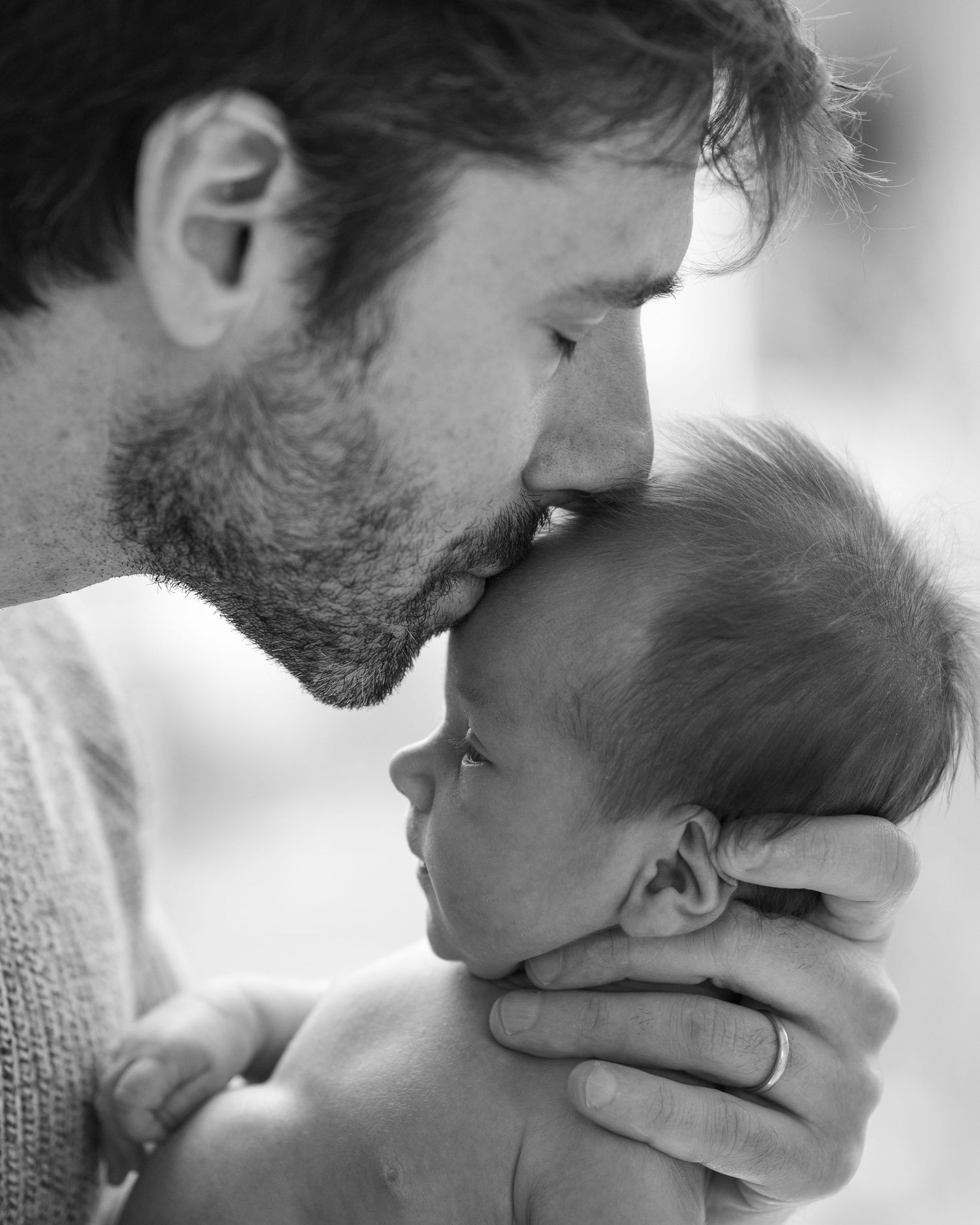 Black and white photos showing gentle kisses between parent and newborn.