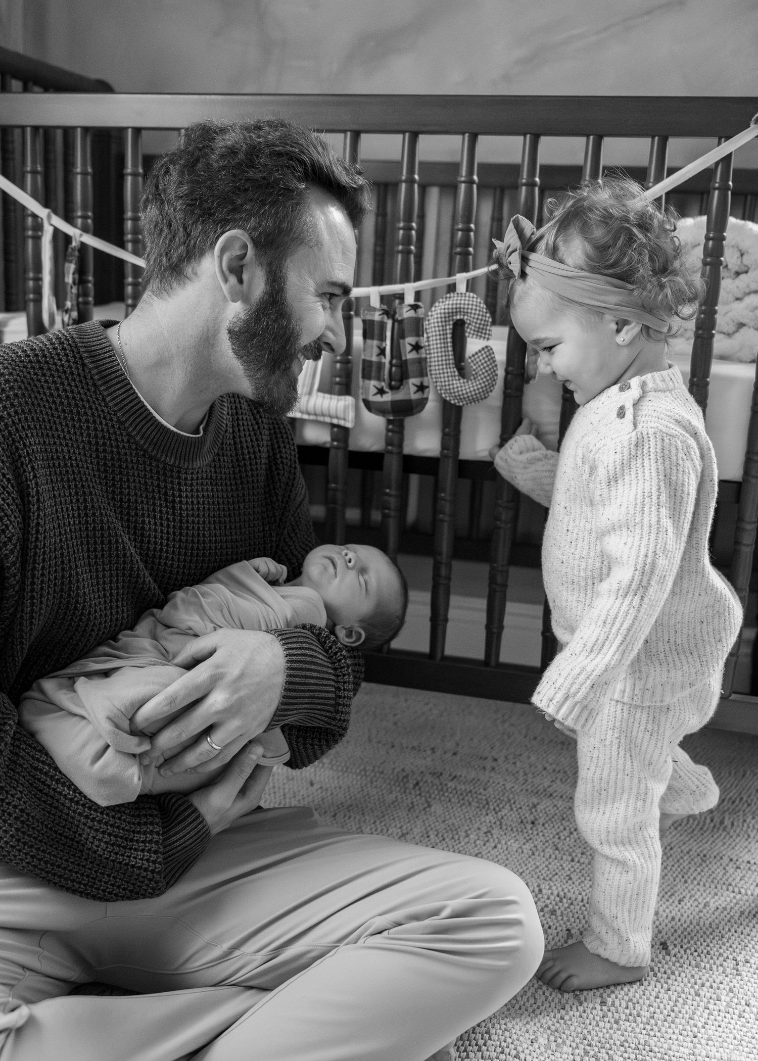 A sequence of black and white photos showing tender playtime moments on a carpeted floor.