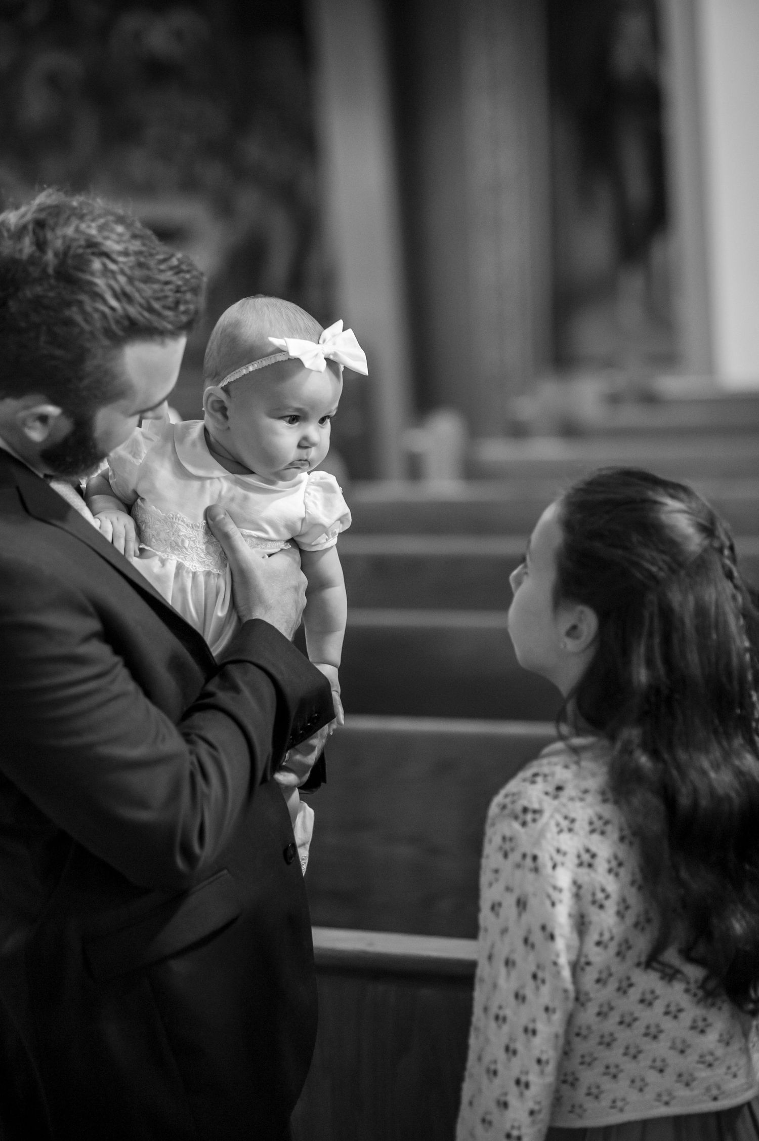 A sequence of black and white photos showing tender moments between a baby and parents in formal attire.
