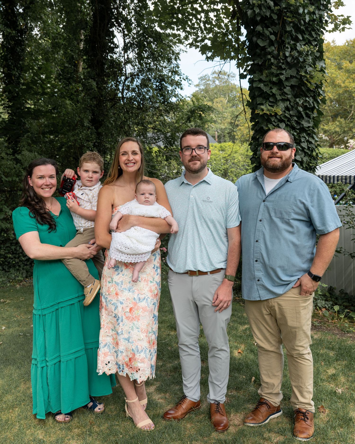 A family photo series outdoors with coordinated outfits in green and gray tones.