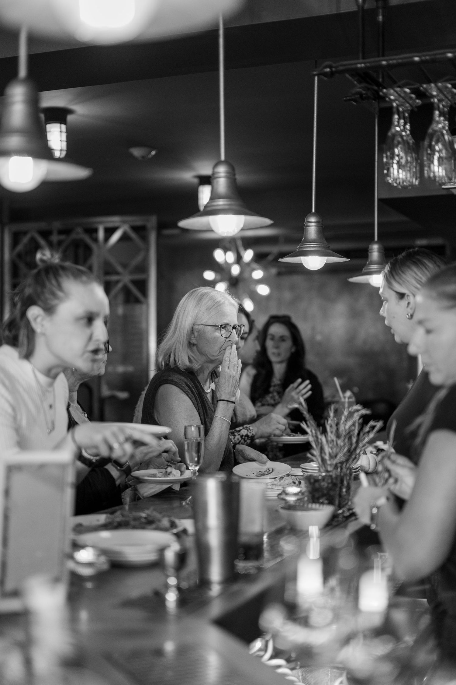 People gathered around a long table for a meal in a dimly lit restaurant setting.