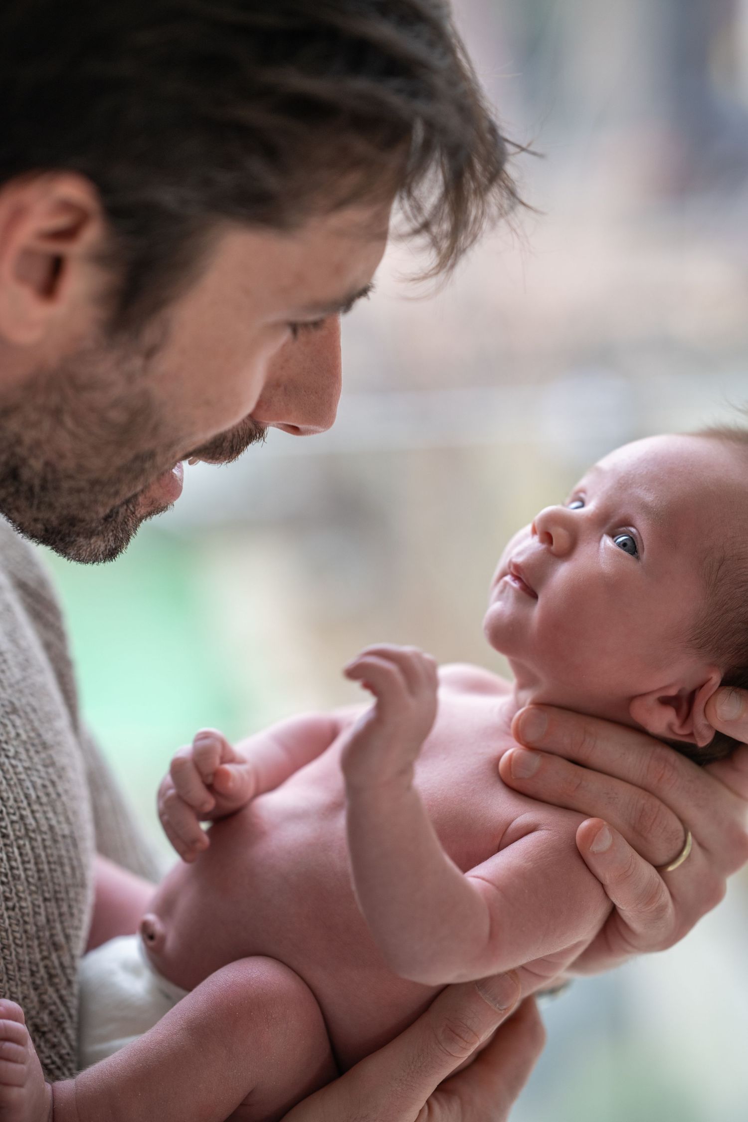 Tender moment between parent and newborn baby in soft natural light.