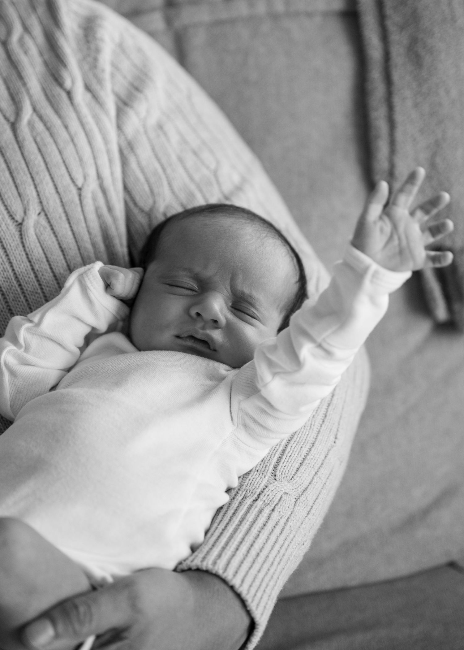 Black and white portraits of a peaceful sleeping newborn in white clothing.