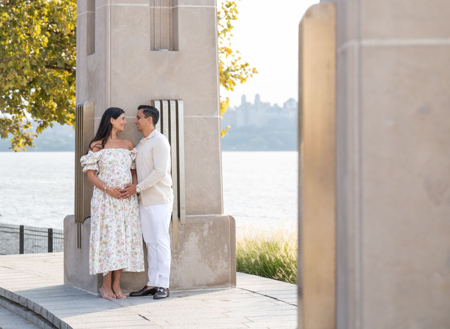 Romantic couple portrait session under columned architecture by the water.