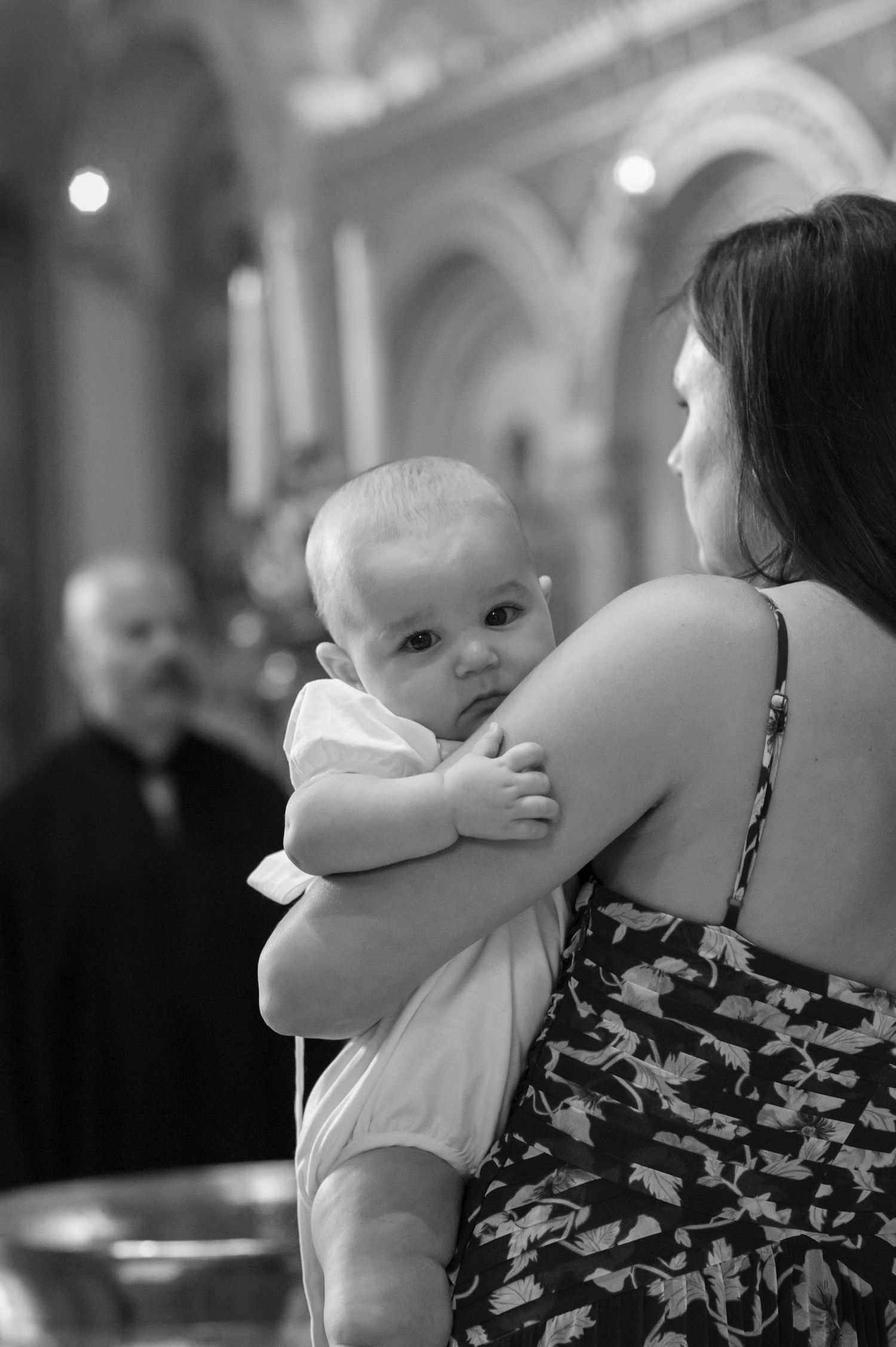 Black and white photos capture intimate moments between an infant and adults at a formal gathering.