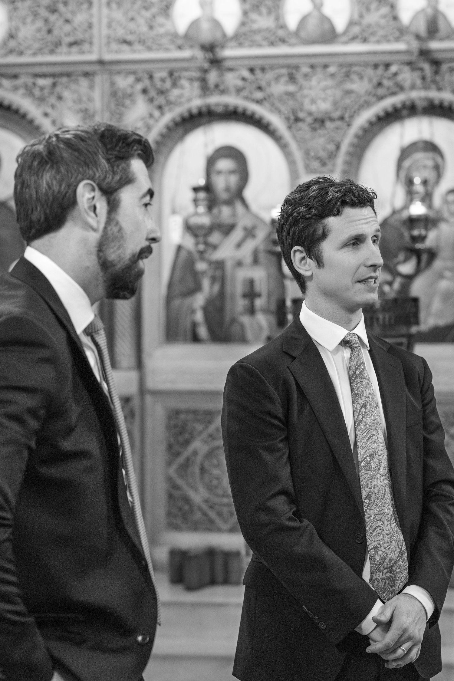 A group in formal attire stands together inside a church with ornate religious artwork and architecture.