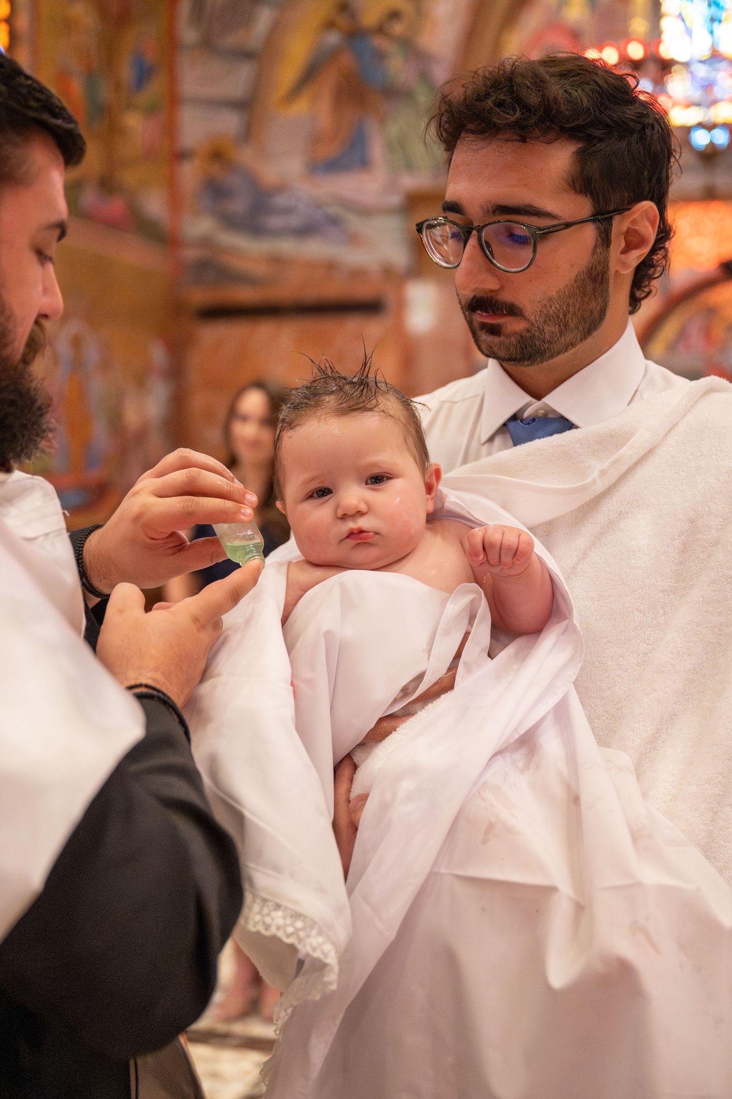 Intimate moments during a baptism ceremony with a baby wearing traditional white baptismal clothing.