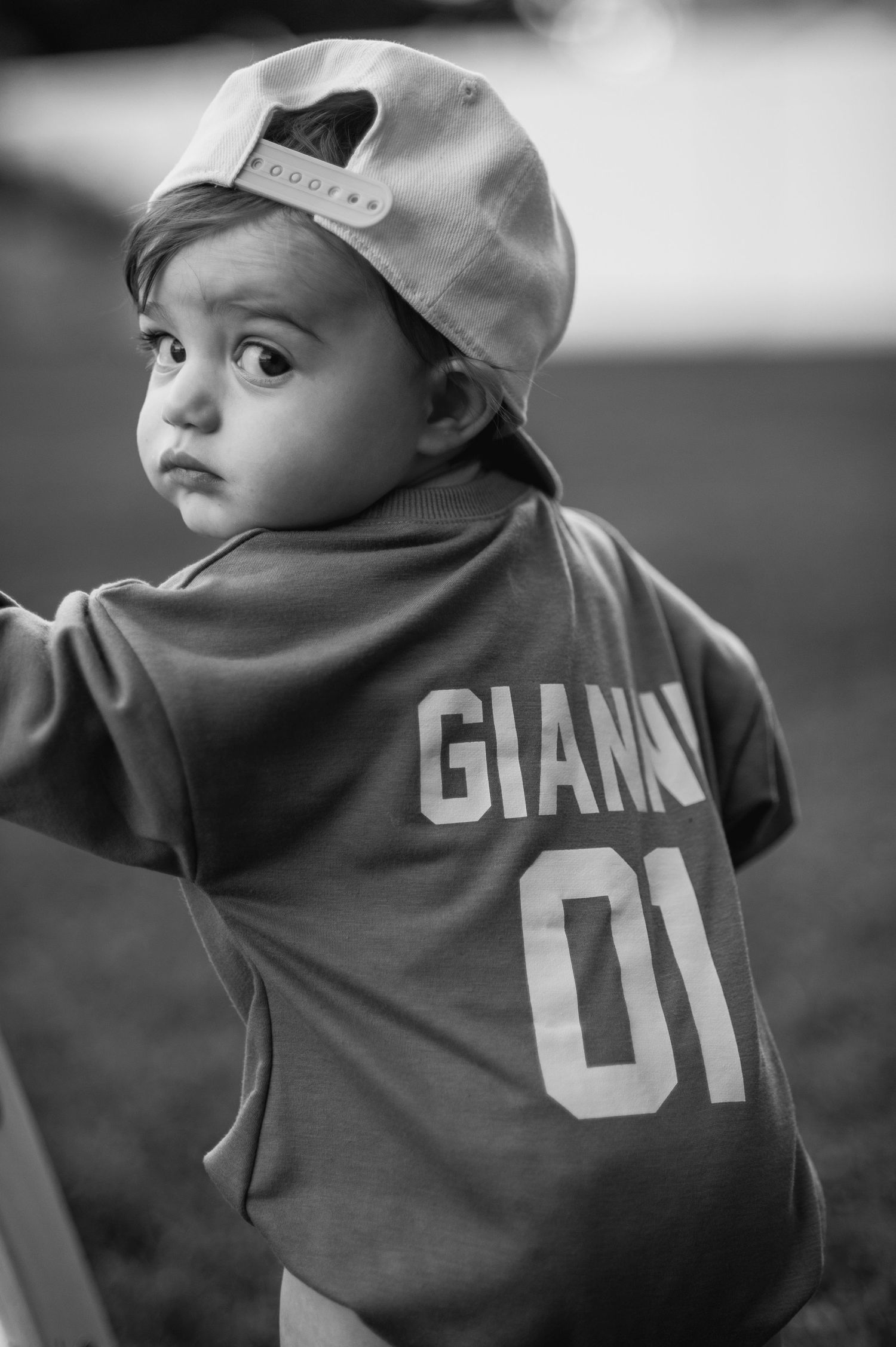 Black and white series of baby wearing Giants sports jersey.