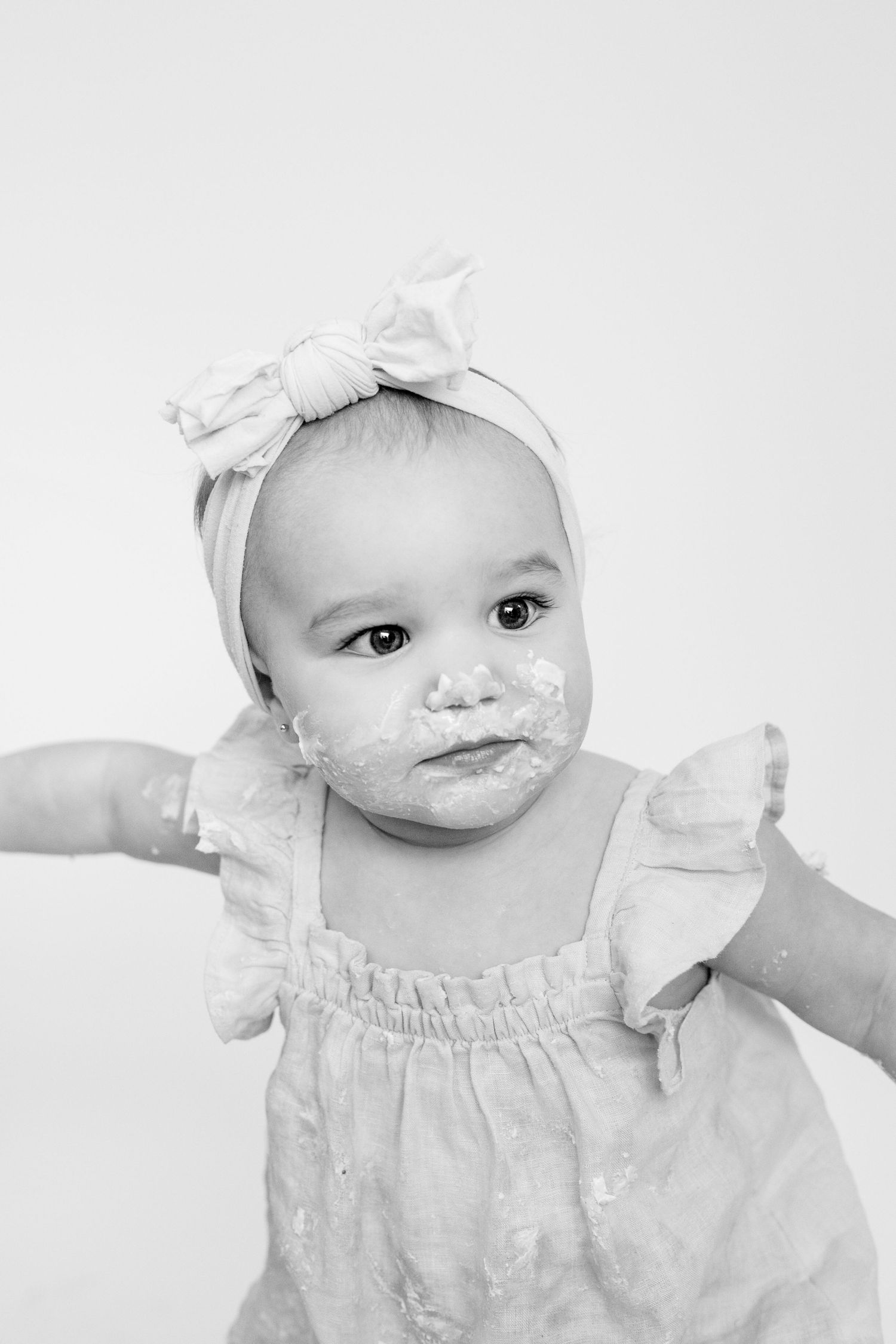 A baby wearing white clothing smiles in a series of black and white portraits.