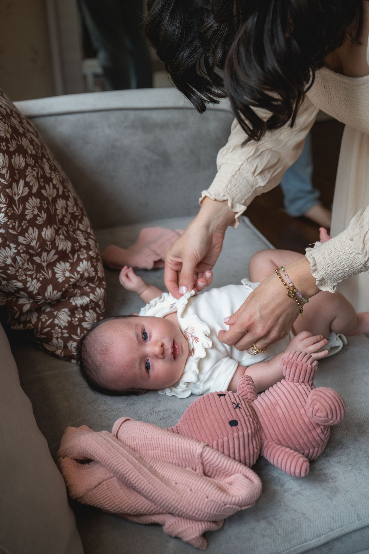 Sequence showing baby in pink striped outfit being changed on grey couch.