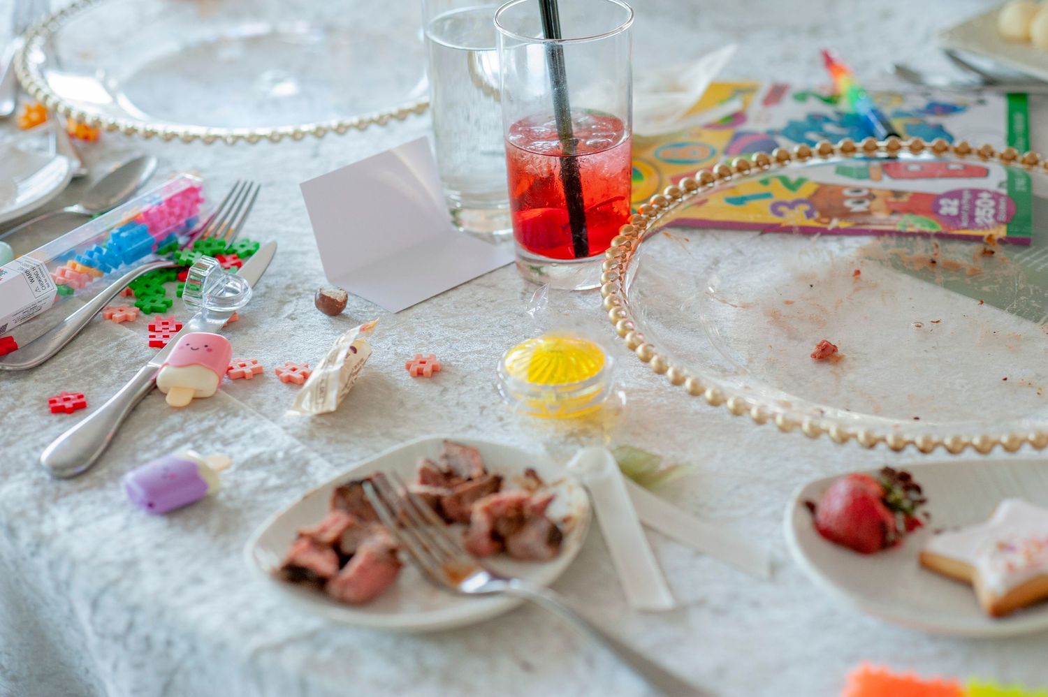 A decorated table with scattered candies, beads and party favors at a celebration.