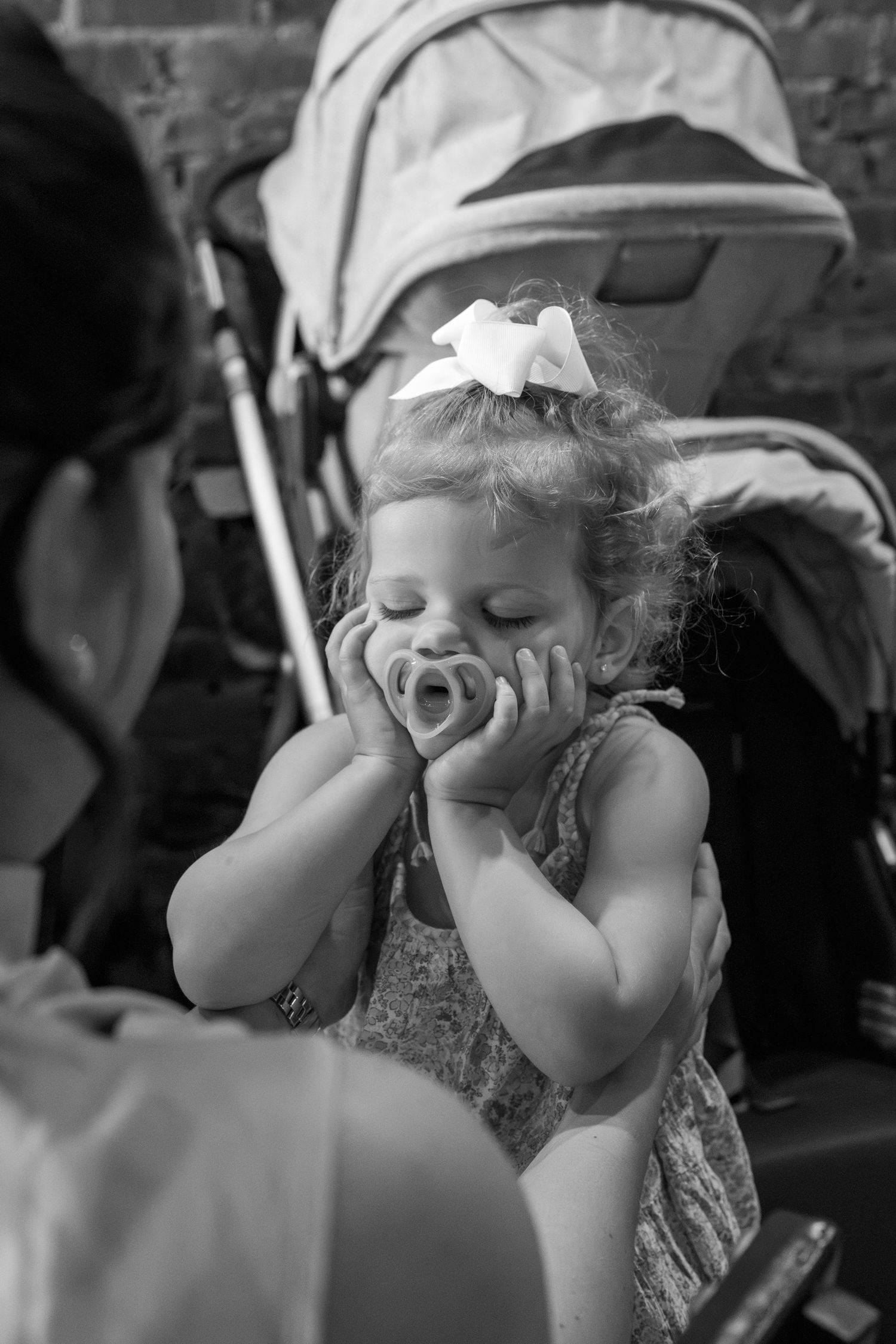 A black and white portrait of a small child in formal wear with eyes closed and a delighted expression.