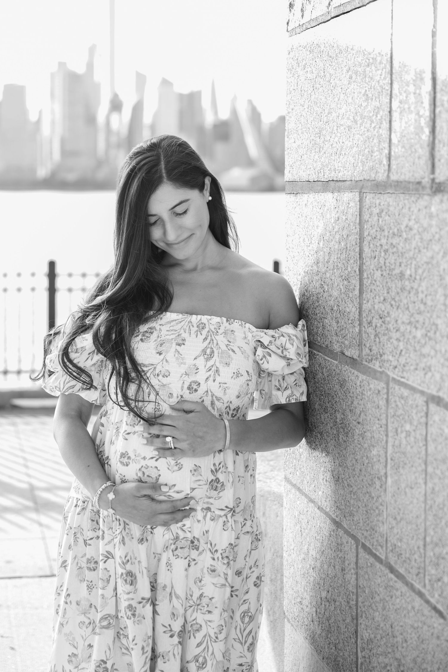 A person in a floral off-shoulder dress poses against a wall in a series of black and white photos.