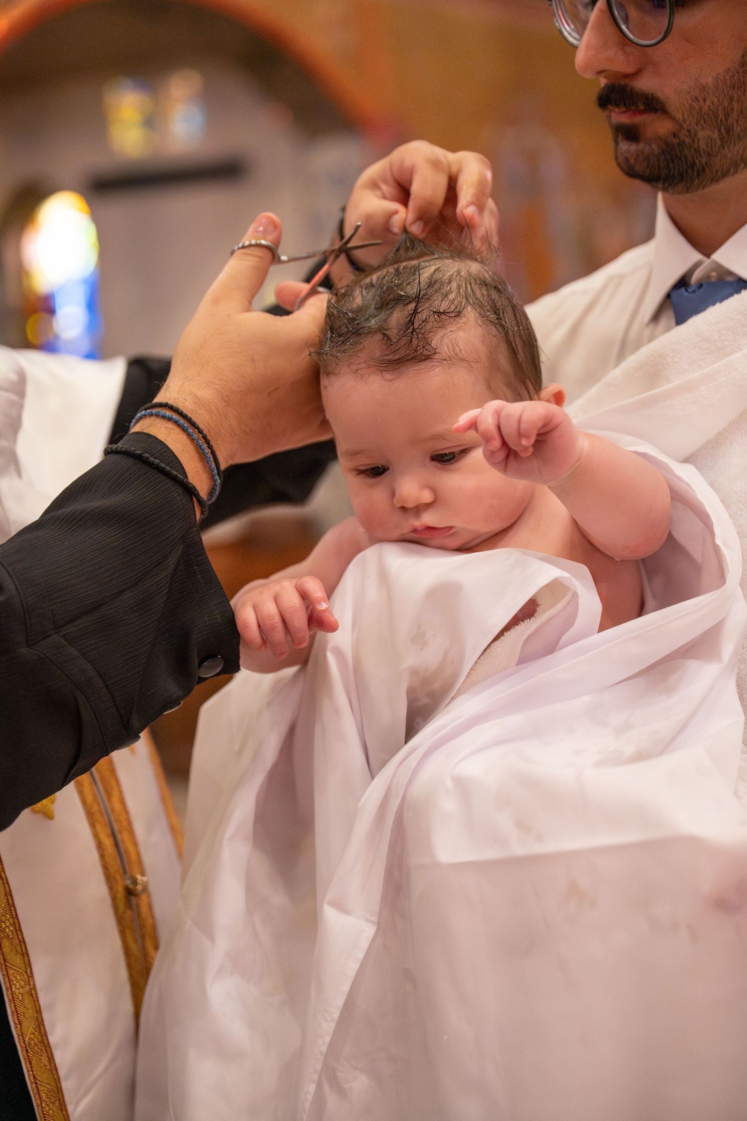 A series of photos showing a baby in white clothing during a religious baptism ceremony.