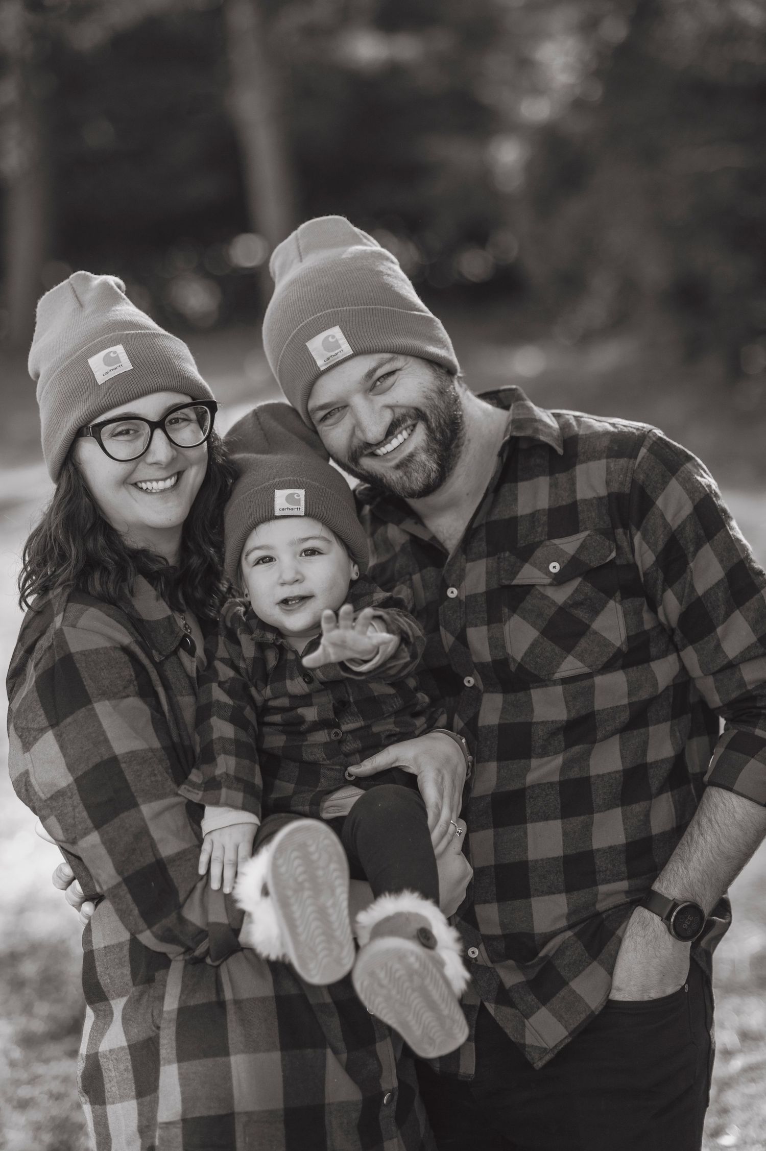 Winter family portrait in coordinating buffalo plaid and matching beanies outdoors.